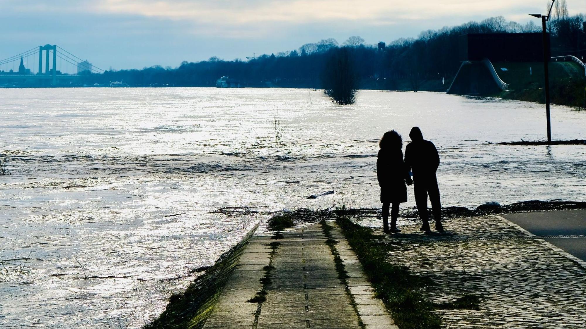Ein Paar steht an einer vom Rhein überspülten Rampe.