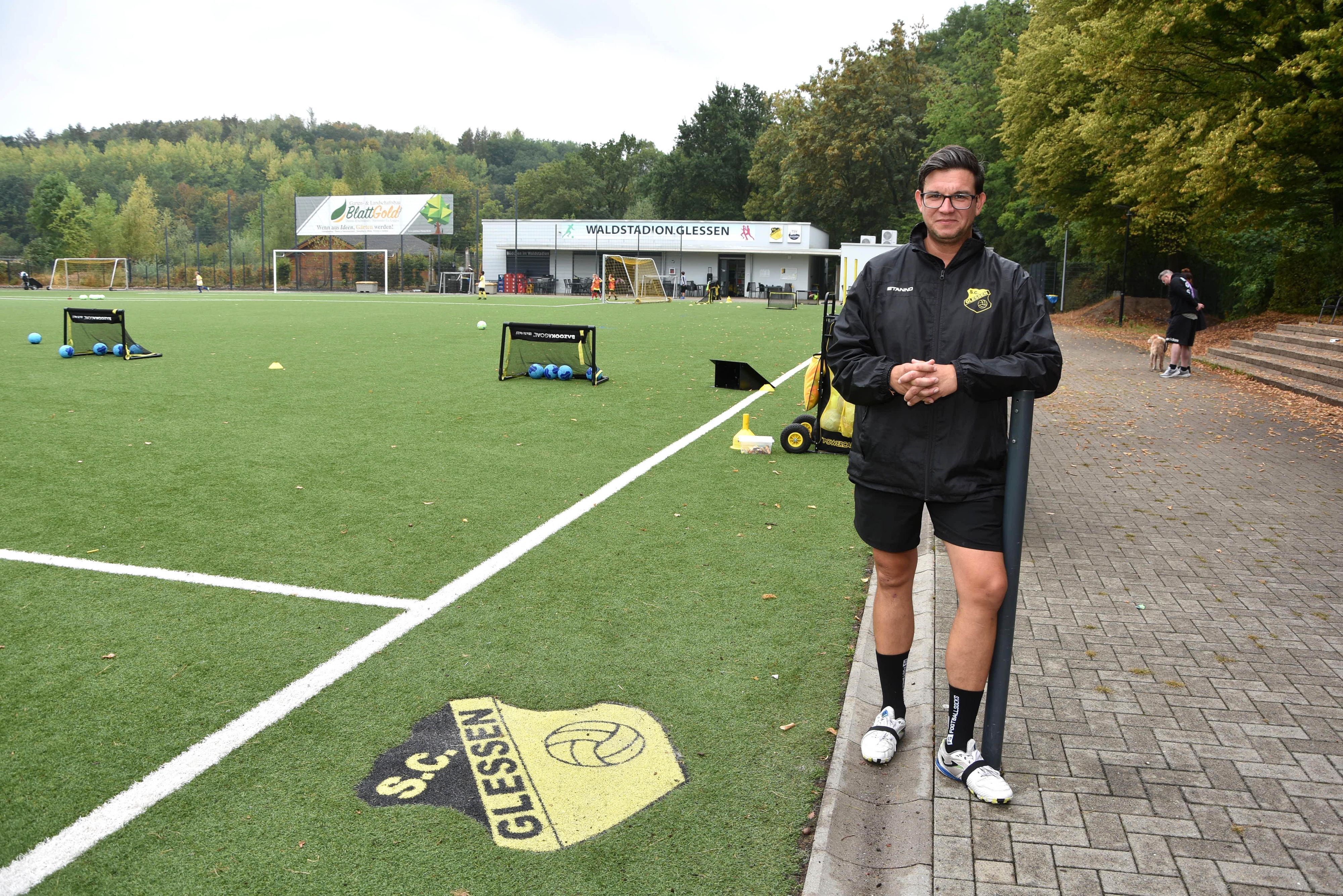 Ein Mann steht neben der Seitenlinie eines Fußballplatzes.