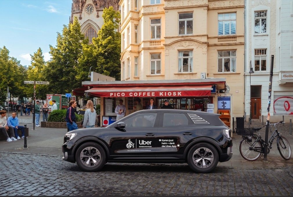 Ein Uber-Fahrzeug steht vor einem Kiosk.