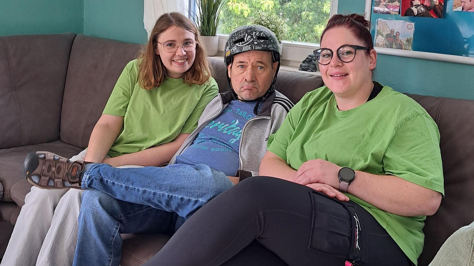Das Foto zeigt drei Personen auf einem Sofa.