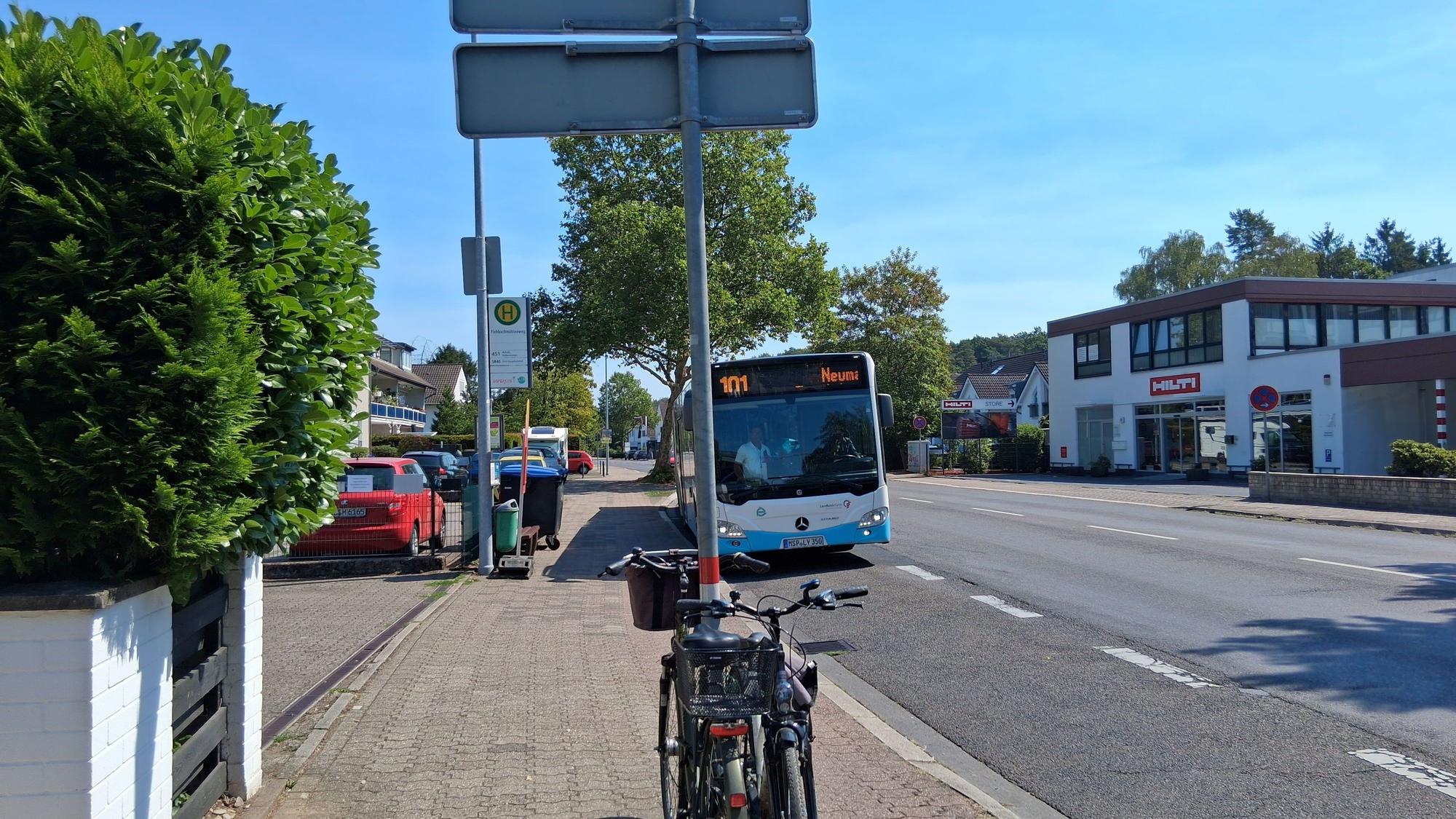 Zu sehen ist ein Bus auf einer Straße, die Sonne scheint.