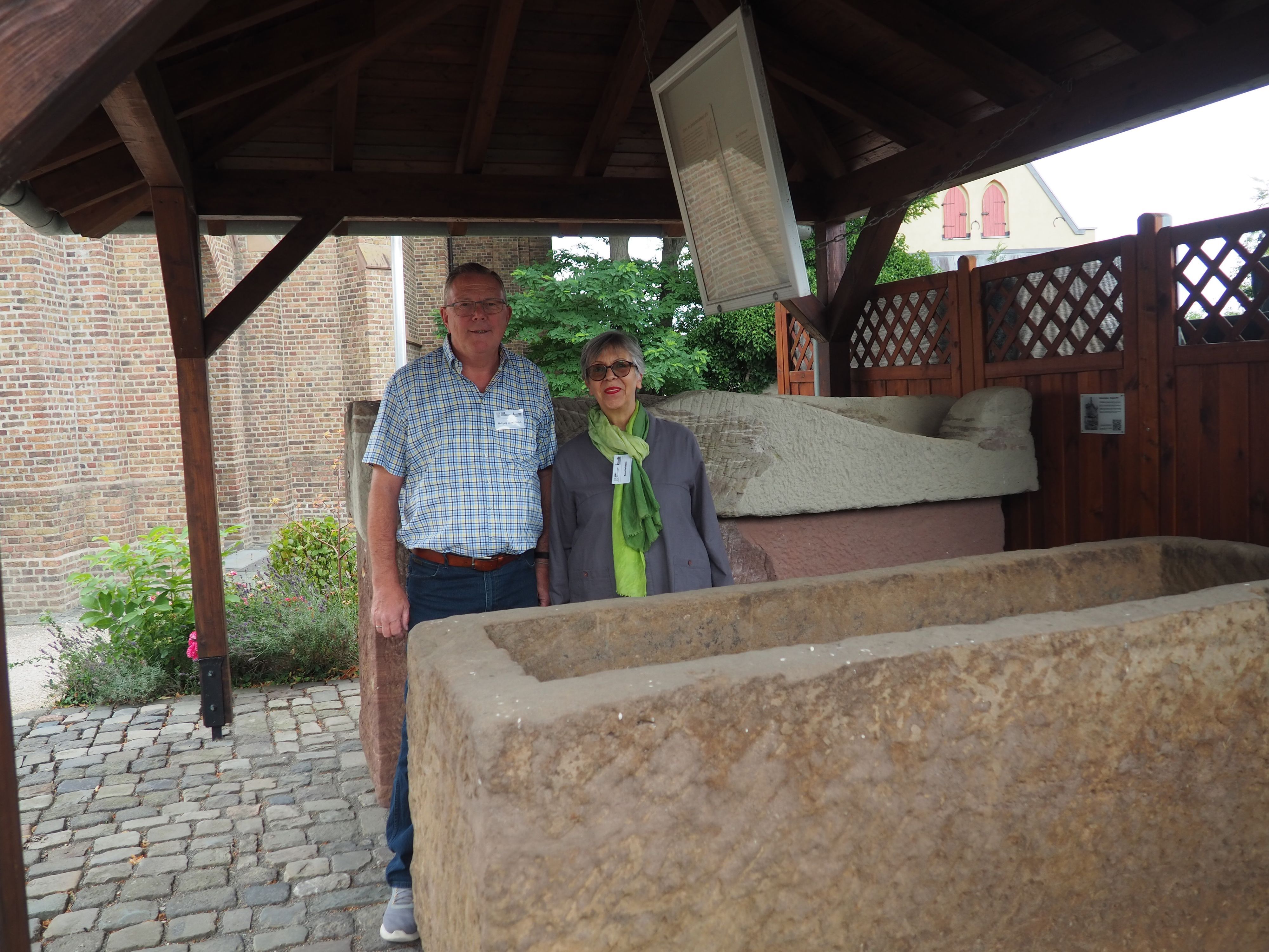 Ein Mann und eine Frau stehen zwischen zwei Steinsärgen.