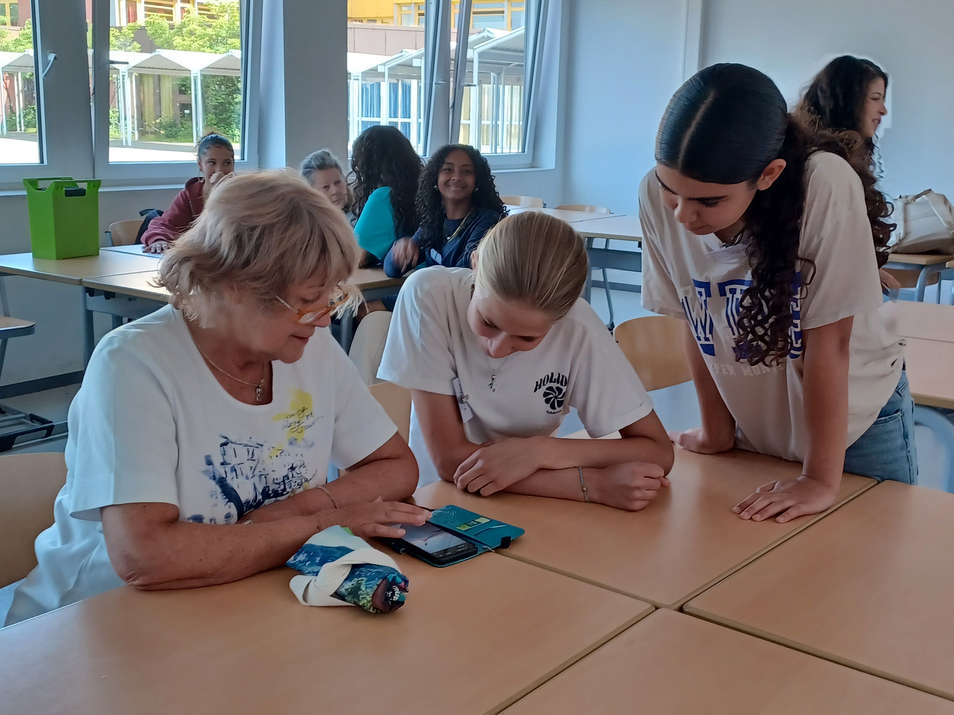 Mehrere Schülerinnen des Gymnasiums Pesch helfen einer Seniorin bei ihren Fragen zu Smartphone und Tablet.