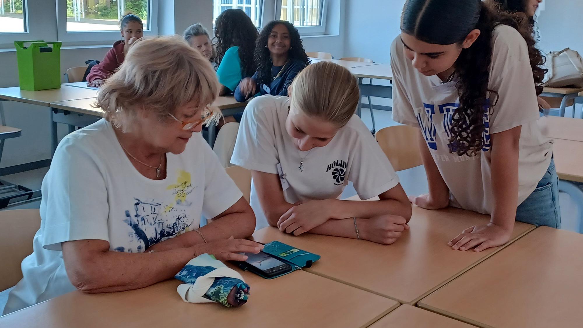 Mehrere Schülerinnen des Gymnasiums Pesch helfen einer Seniorin bei ihren Fragen zu Smartphone und Tablet.