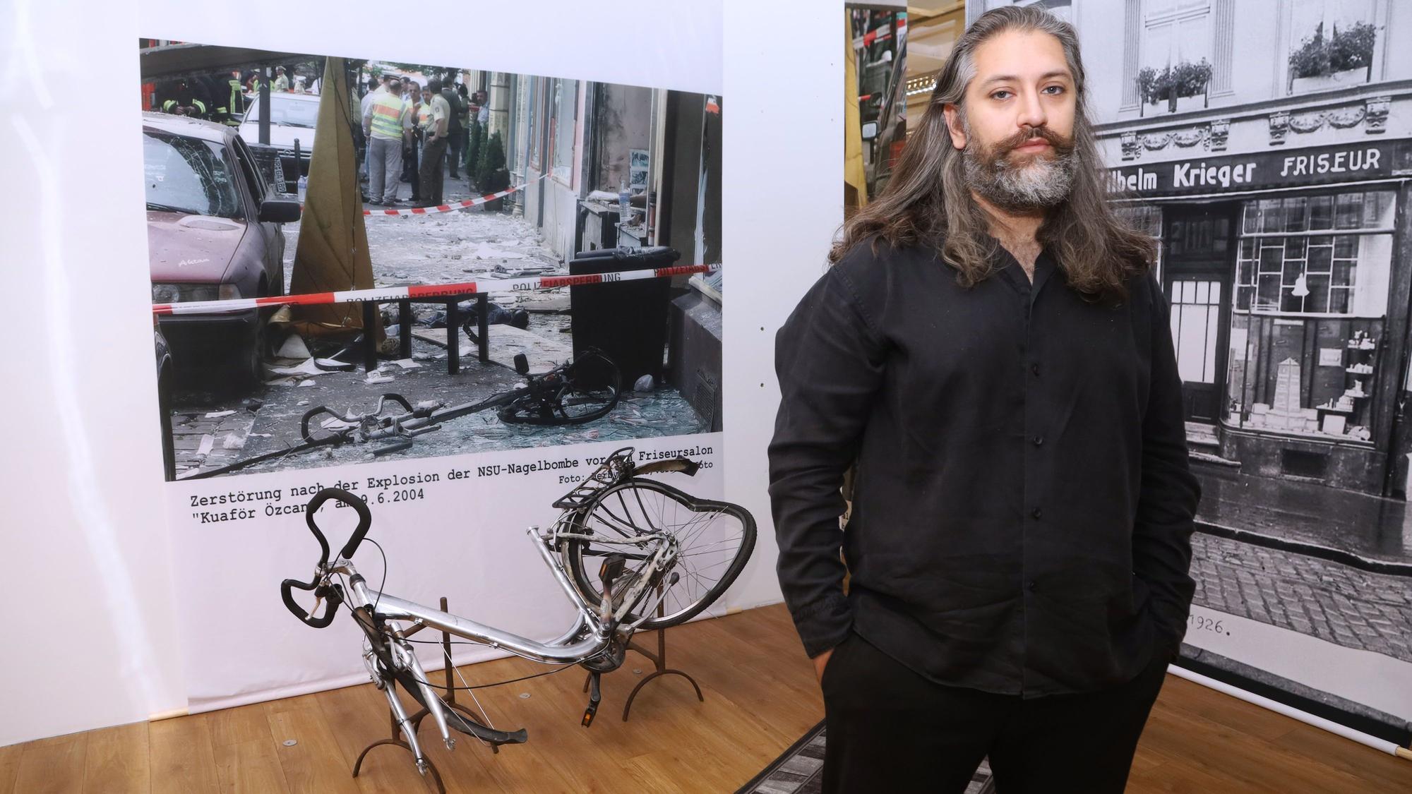 Hüseyin Topel, Vorsitzender der Bildungsinitiative, vor der Nachbildung des demolierten Fahrrads, auf dem die Nagelbombe platziert war.