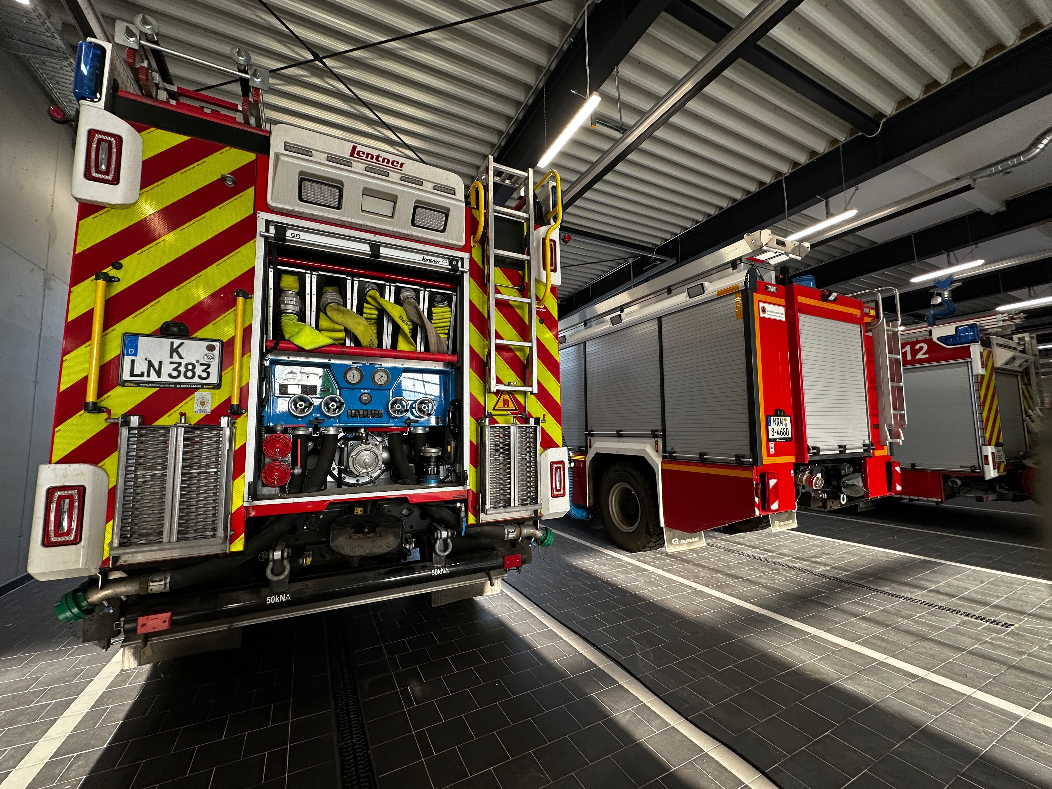 Drei Feuerwehrfahrzeuge stehen nebeneinander in dem neuen Gebäude der Feuerwache Rodenkirchen.