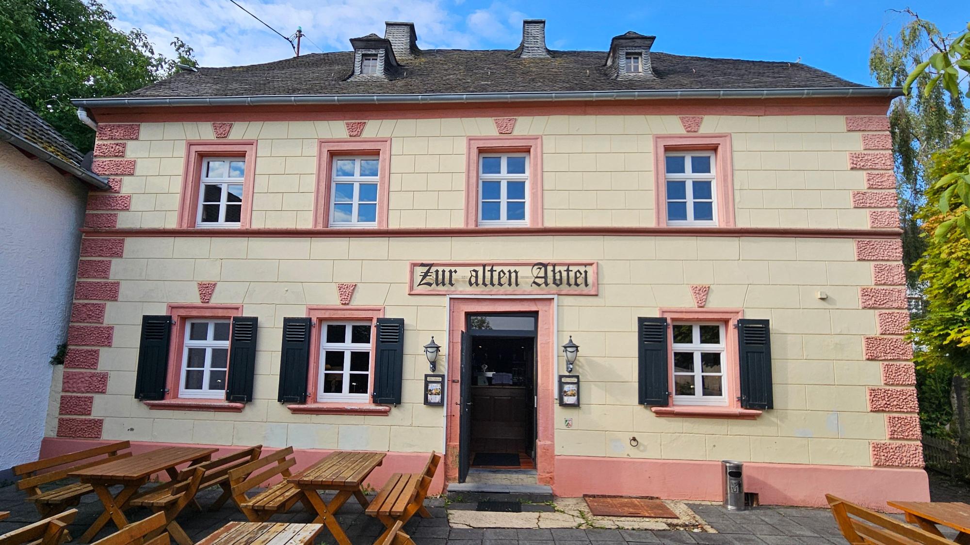 Blick auf die Fassade des Hauses mit dem Schild „Zur alten Abtei“ über der Tür.