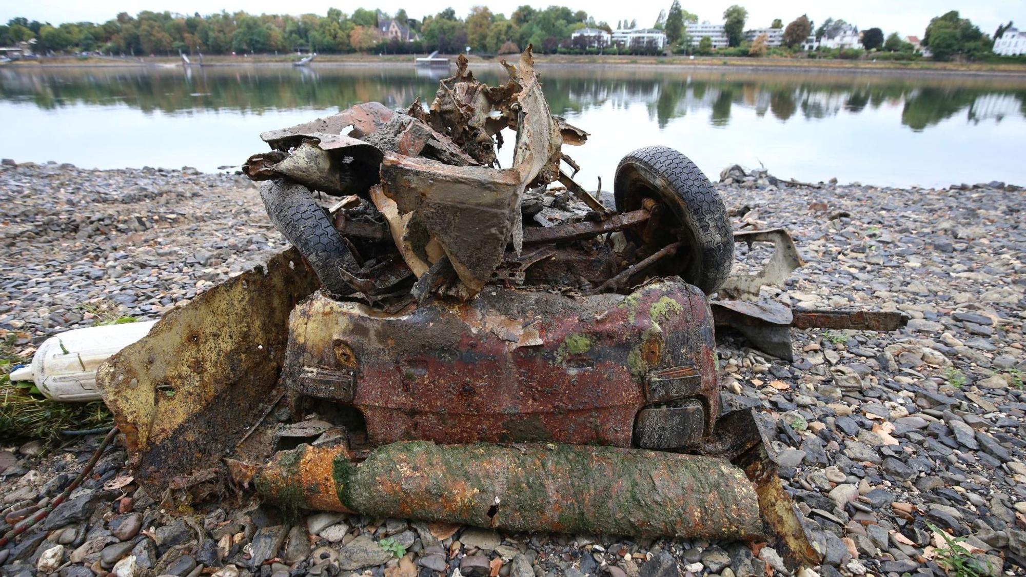 Ein verrostetes Autowrack am Rheinufer.