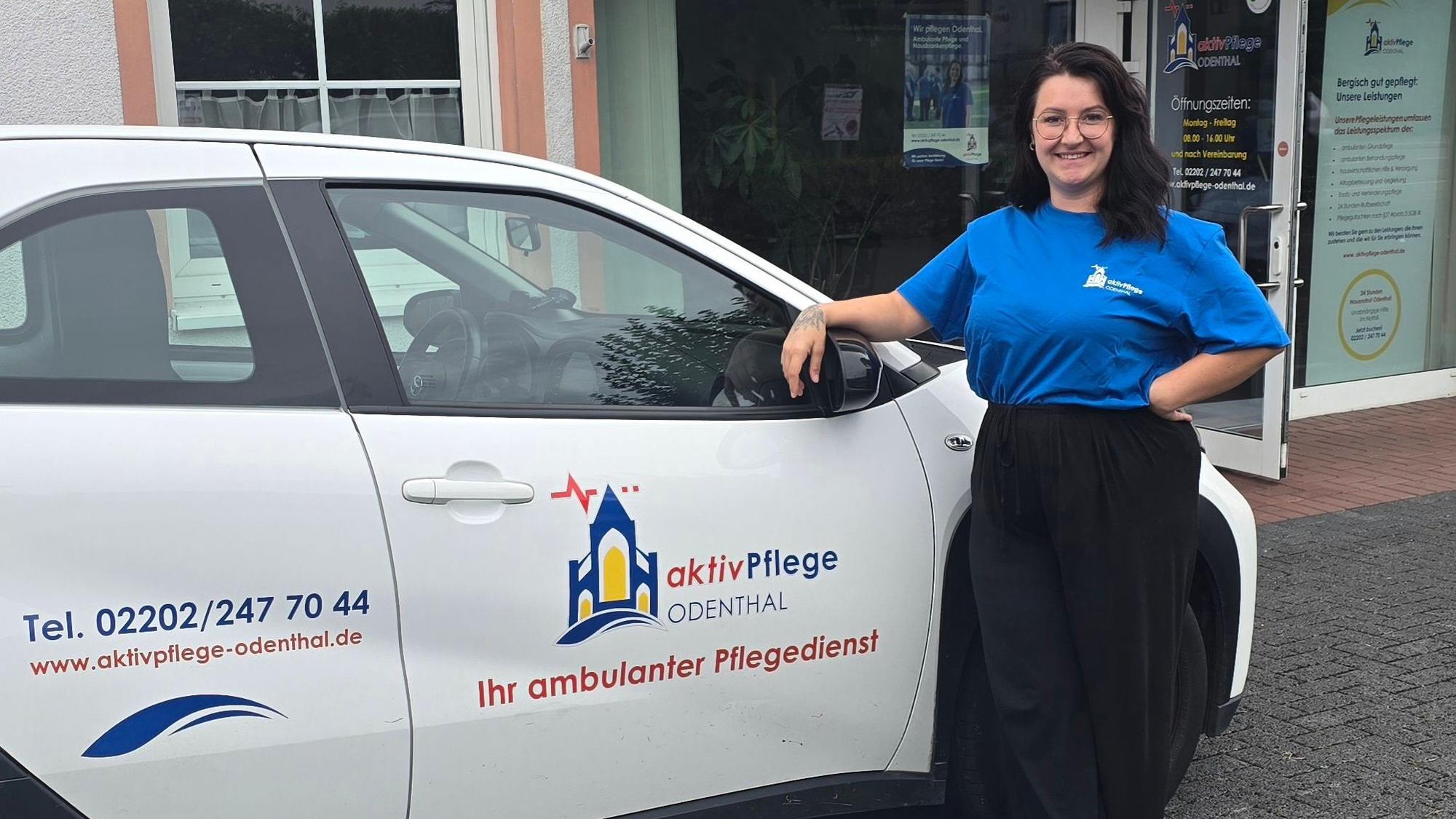 Zu sehen ist eine junge Frau vor einem Firmenwagen.