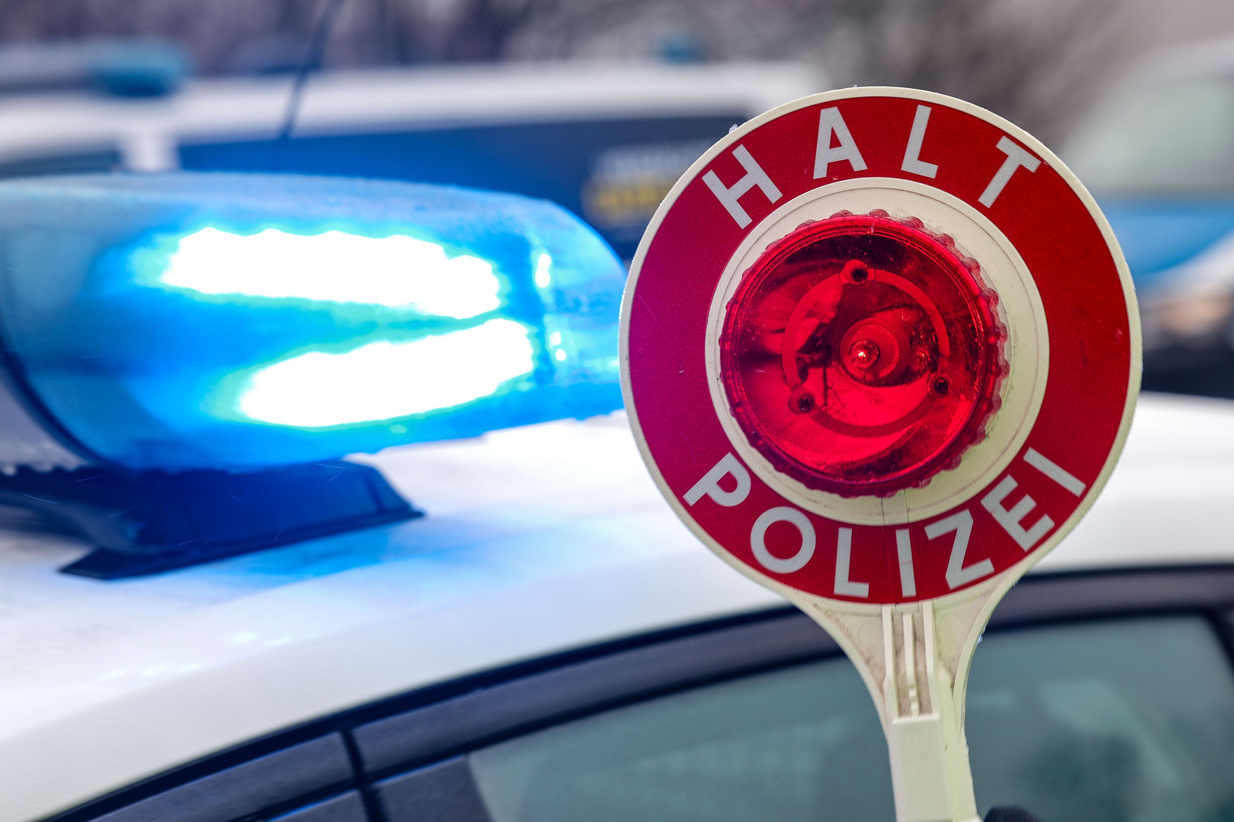Ein Polizist hält eine Polizeikelle für eine Kontrolle.