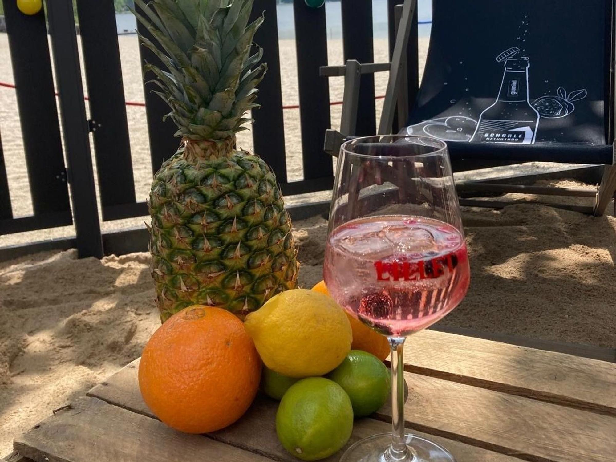 Auf dem Bild sind ein gefülltes Weinglas und Obst zu sehen.