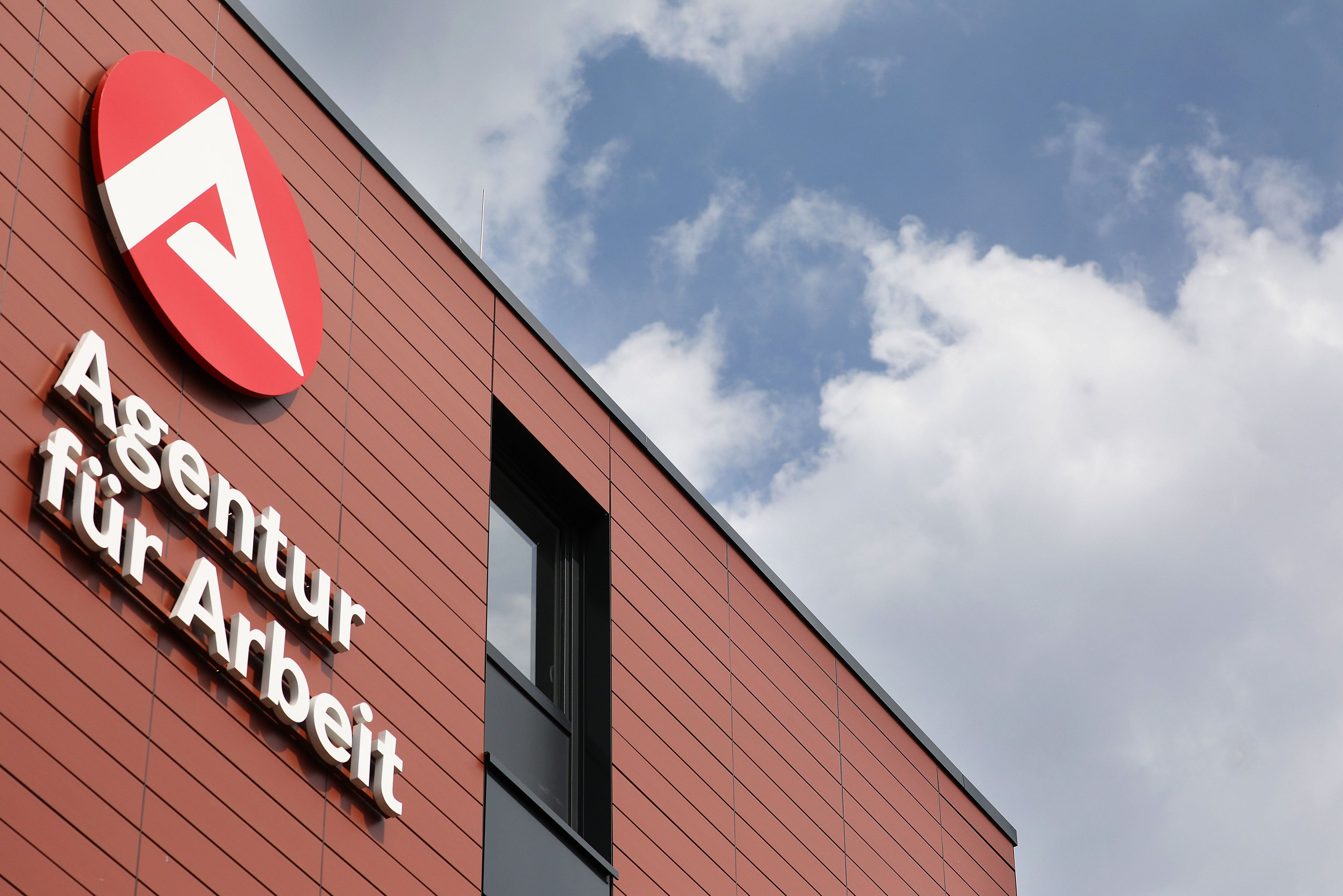 Ein Logo hängt am Gebäude der Agentur für Arbeit.