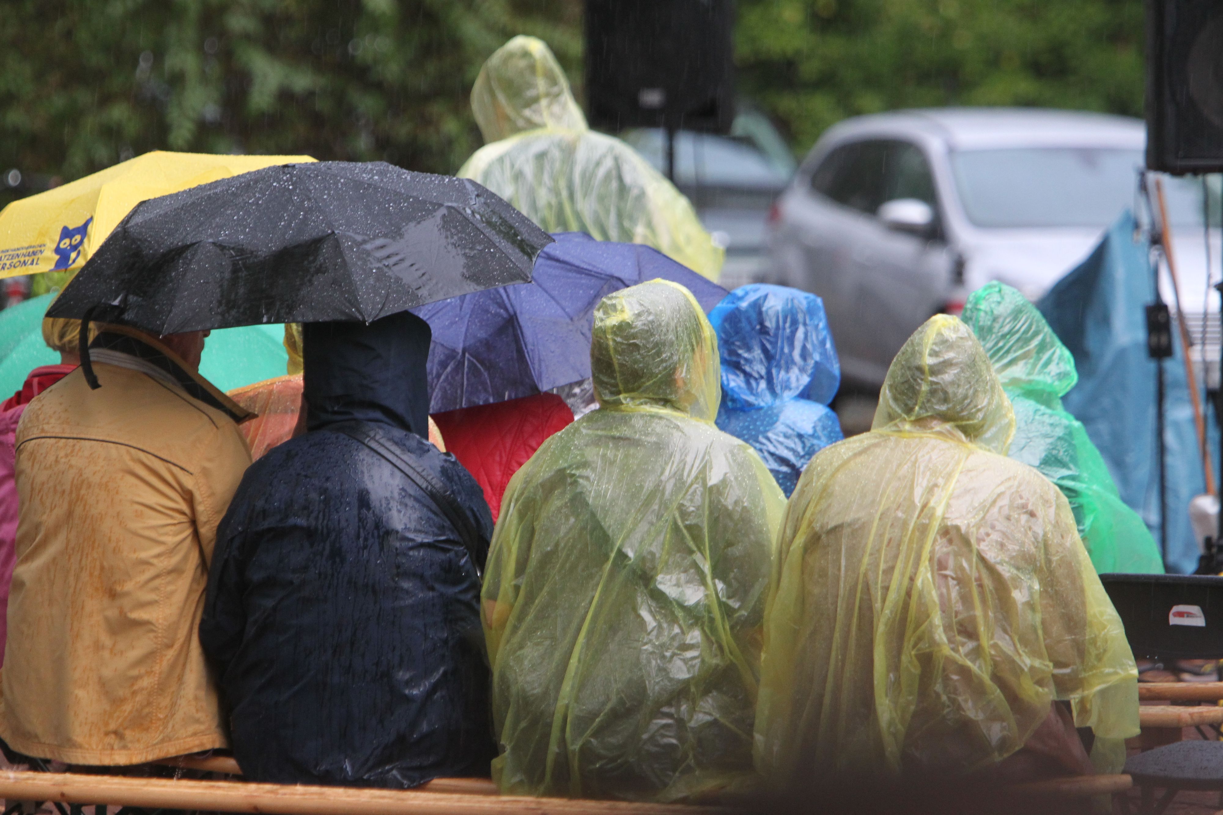 Unter gelben Regencapes der Stadtwerke schützen sich die Besucher vor dem schlechten Wetter.