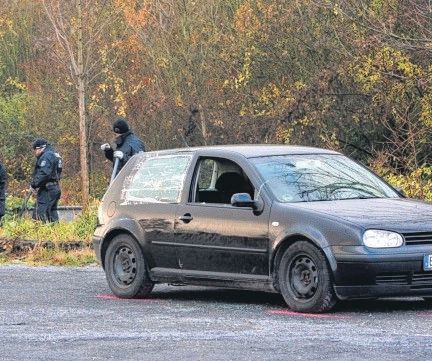 Zu sehen ist ein schwarzer VW Golf, im Hintergrund Polizisten.