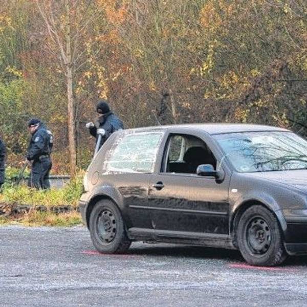 Zu sehen ist ein schwarzer VW Golf, im Hintergrund Polizisten.
