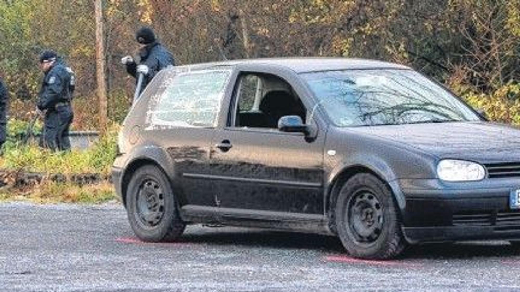 Zu sehen ist ein schwarzer VW Golf, im Hintergrund Polizisten.
