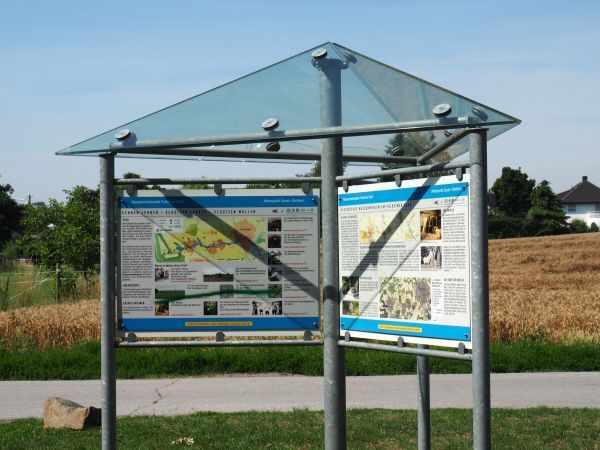 Ein überdachter Pavillon mit Infotafeln.