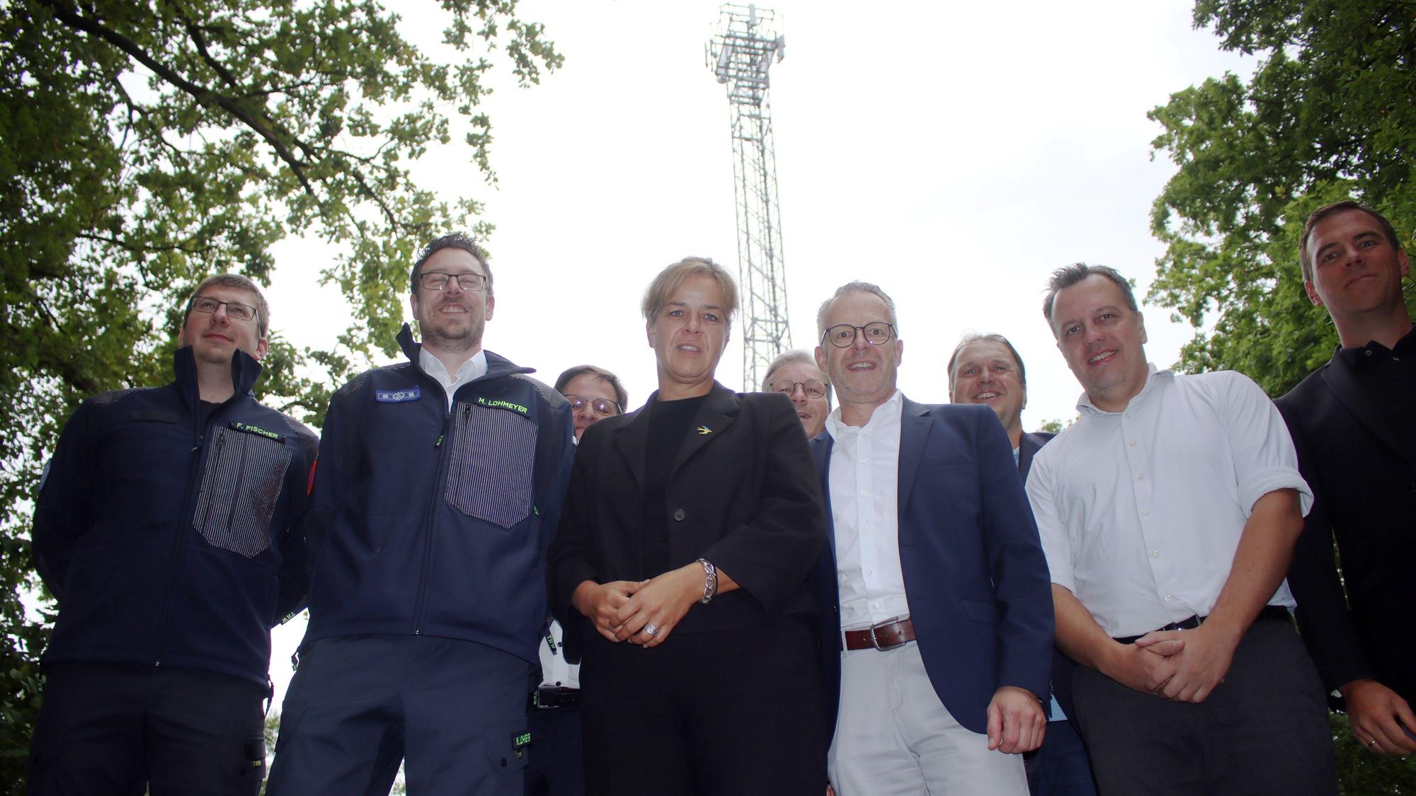 Eine Gruppe Menschen steht vor einem Mobilfunkmast an der Steinbachtalsperre bei Euskirchen.