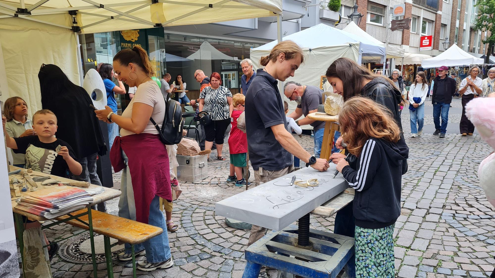 Kinder und Erwachsene beim Bildhauern auf einem Straßenfest