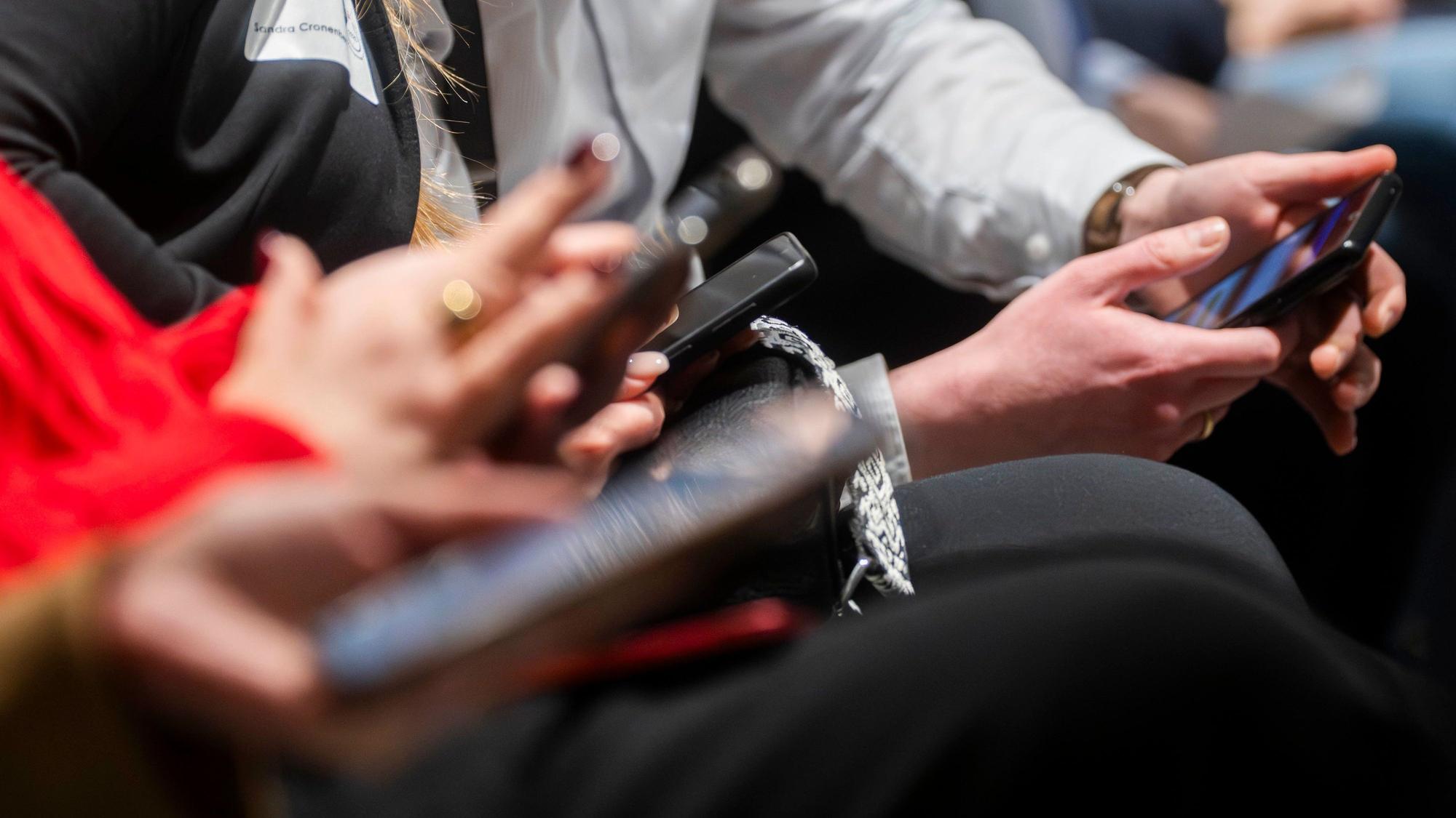 Das Symbolbild zeigt Menschen, die Smartphones bedienen.