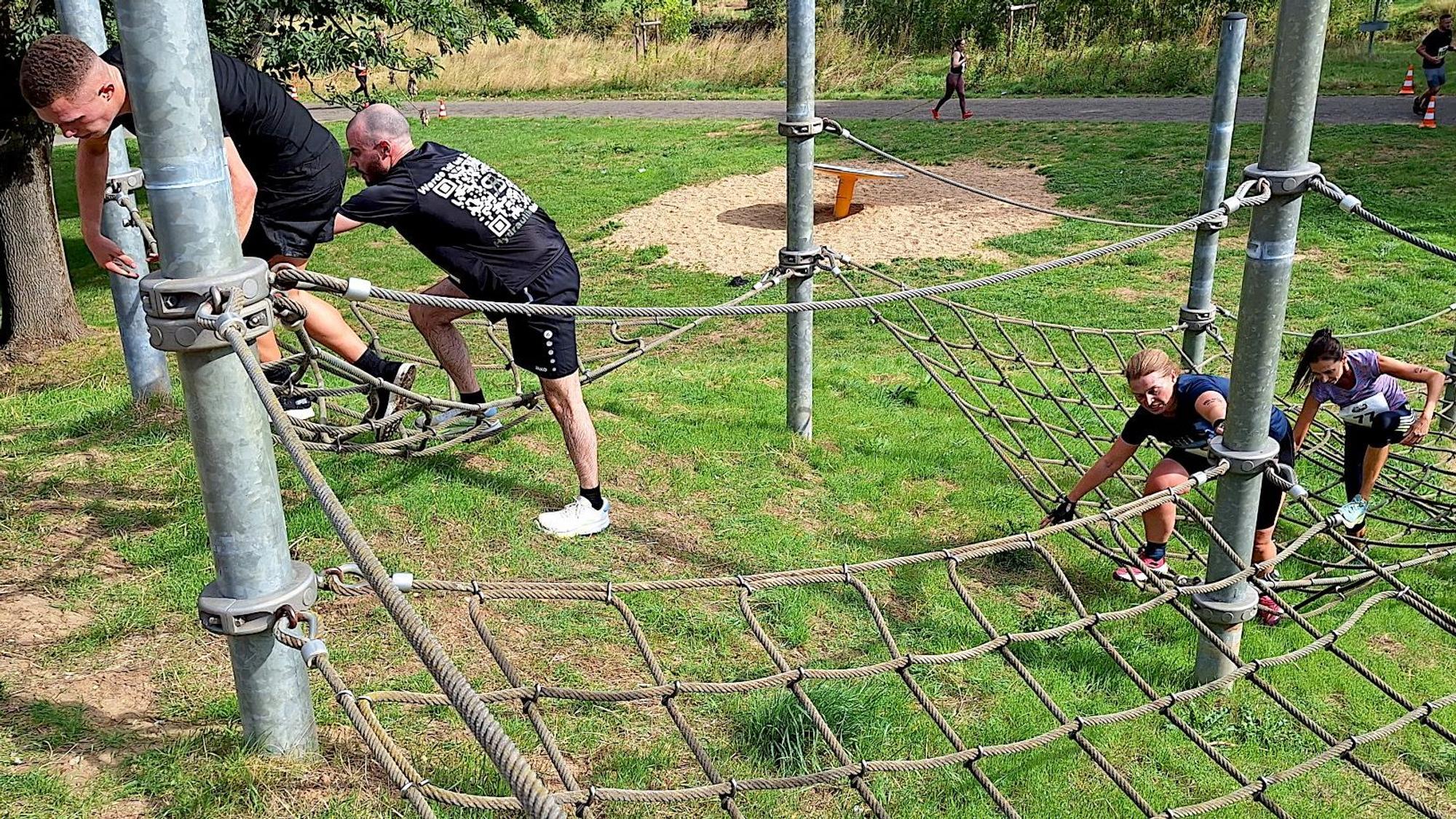 Zwei Männer und zwei Frauen befinden sich auf dem Hindernis.