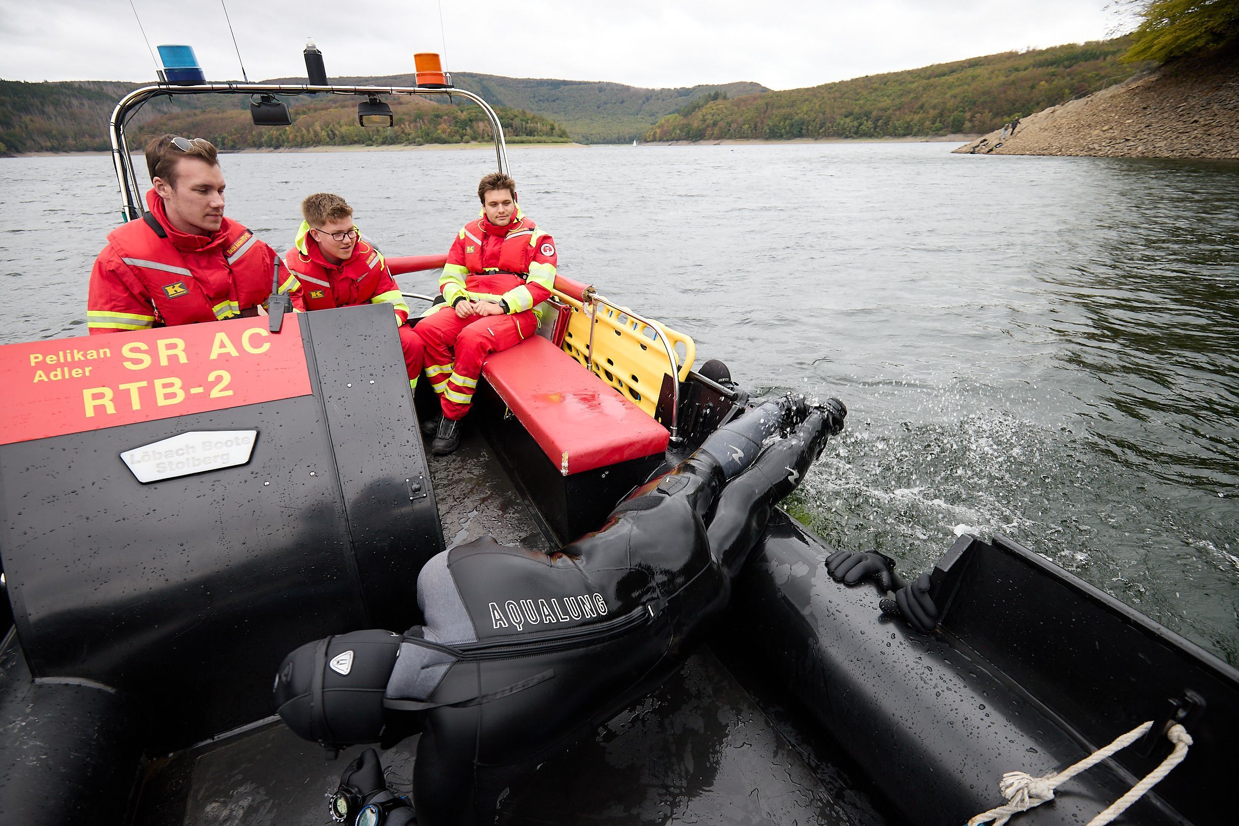 Drei Männer in der typichen rot-gelben Montur der DLRG sitzen in ihrem Boot.