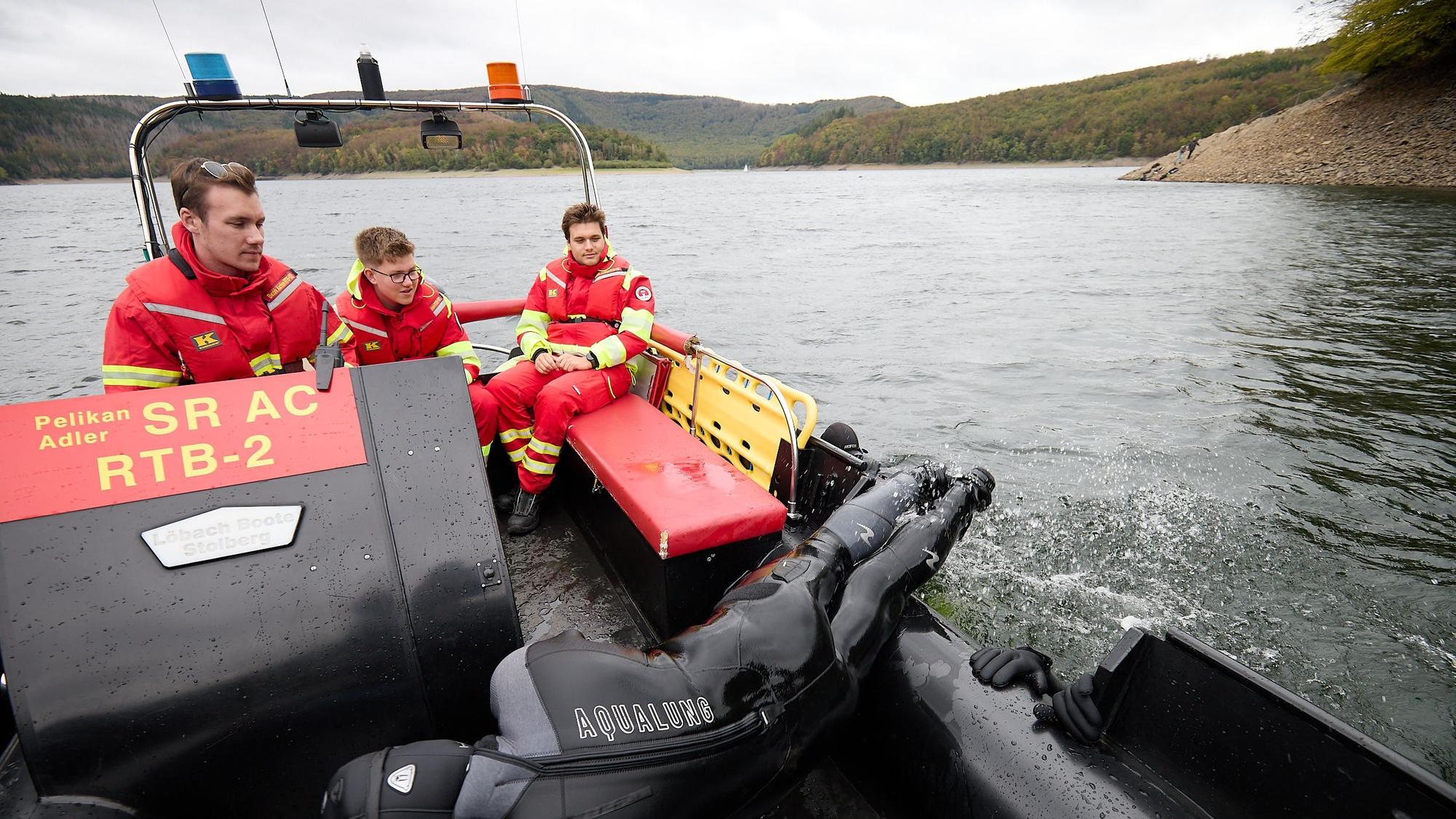 Drei Männer in der typichen rot-gelben Montur der DLRG sitzen in ihrem Boot.