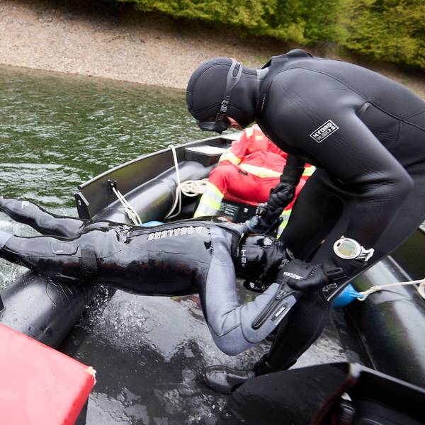 Der Taucher wird von einem Kollegen aus dem Wasser geholt.