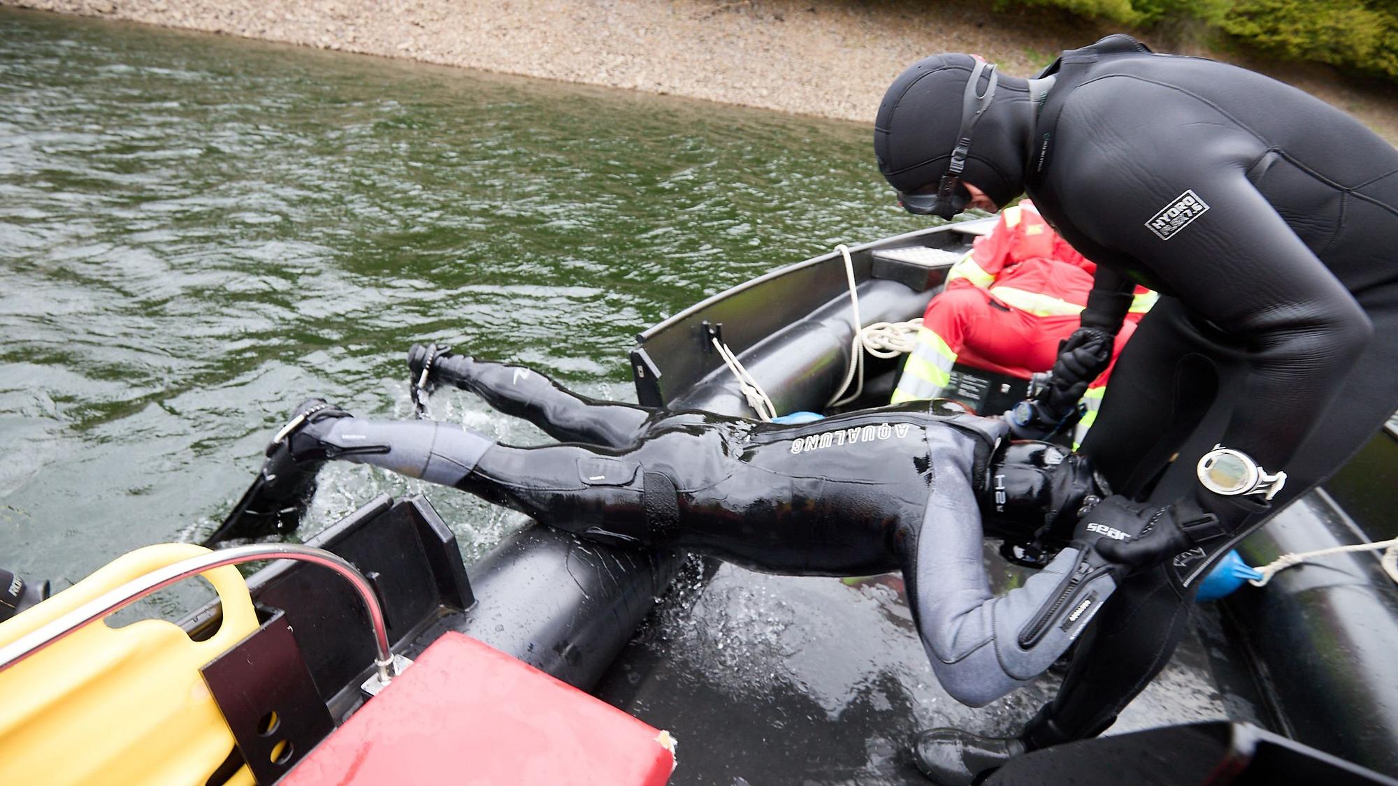 Der Taucher wird von einem Kollegen aus dem Wasser geholt.