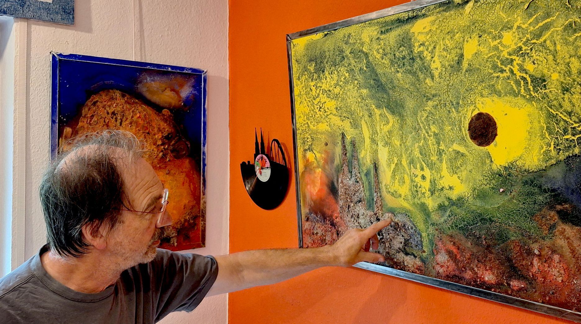 Der Künstler Matthias Hürten steht an einem Bild, dass er aus den verkohlten Überresten eines verbrannten Kunstwerks geschaffen hat.