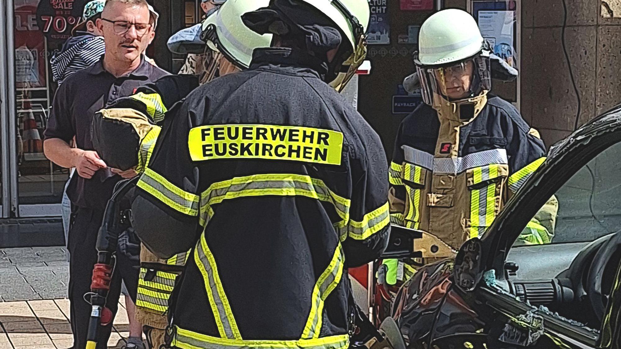 Leute in Feuerwehrausrüstung hantieren mit einem Spreizer an einem Auto.