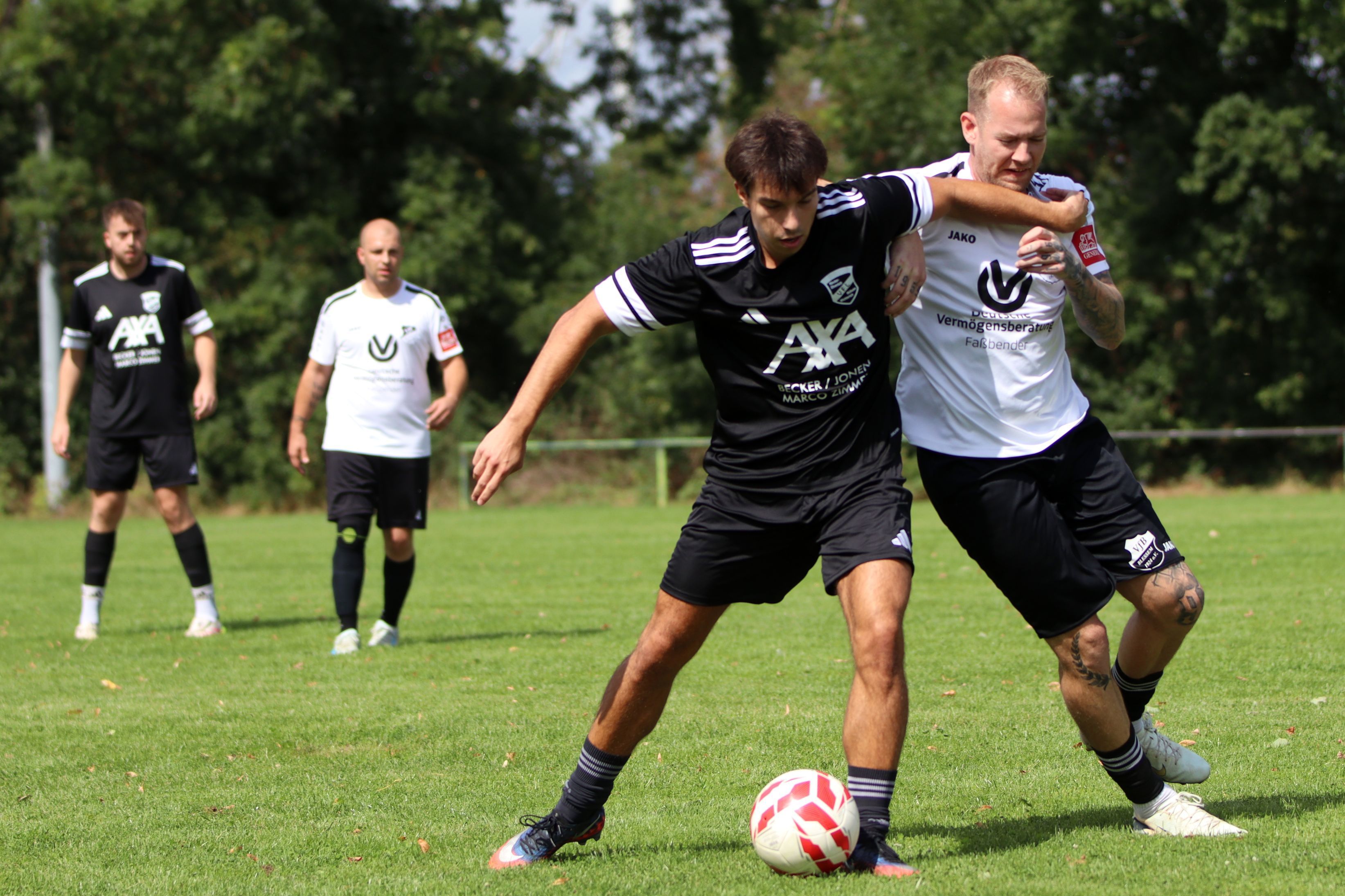 Joe Kajba und Kevin Wulf im Zweikampf, links im Hintergrund beobachten zwei weitere Spieler das Geschehen.