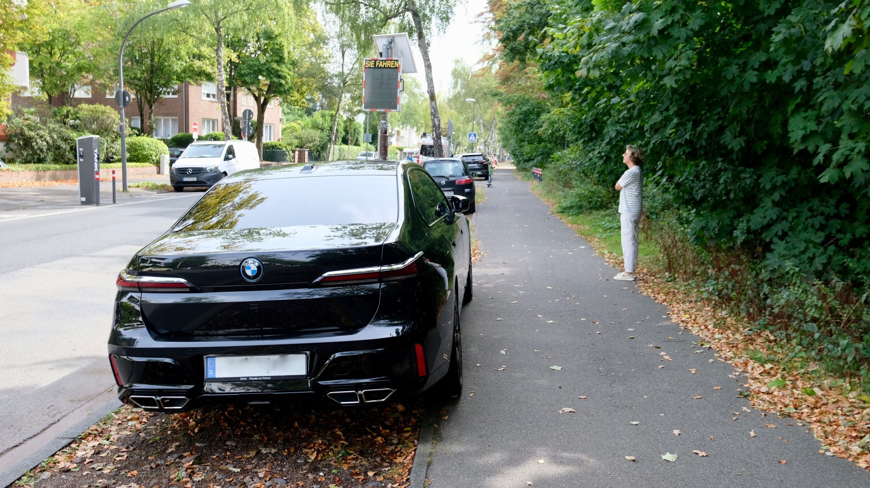 Eine Frau inspiziert den Schotterstreifen neben der Friedrich-Schmidt-Straße, wo wieder viele Menschen ihr Auto geparkt haben, die nicht wissen, dass es dort verboten ist.