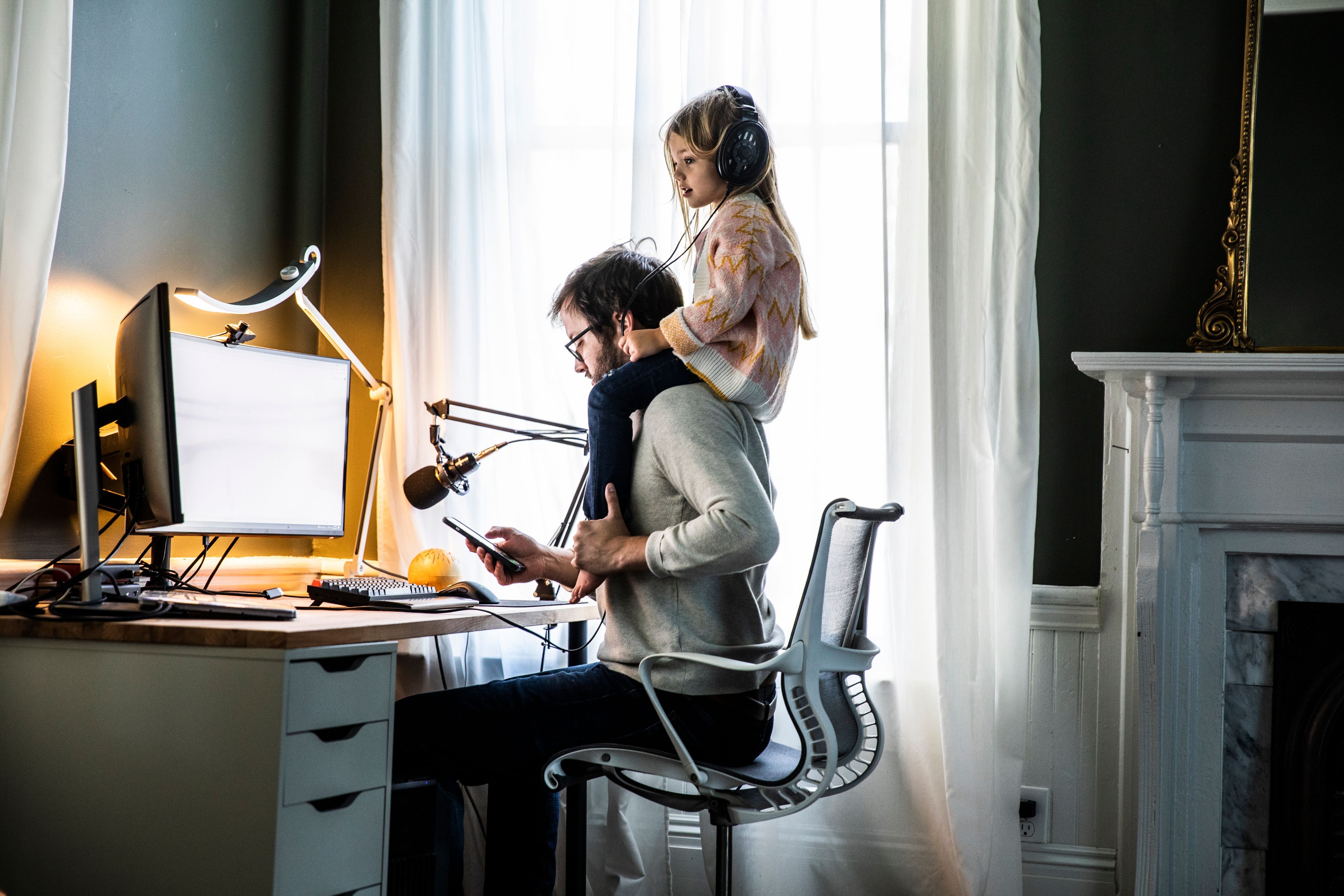 Vater im Büro mit Tochter auf den Schultern.
