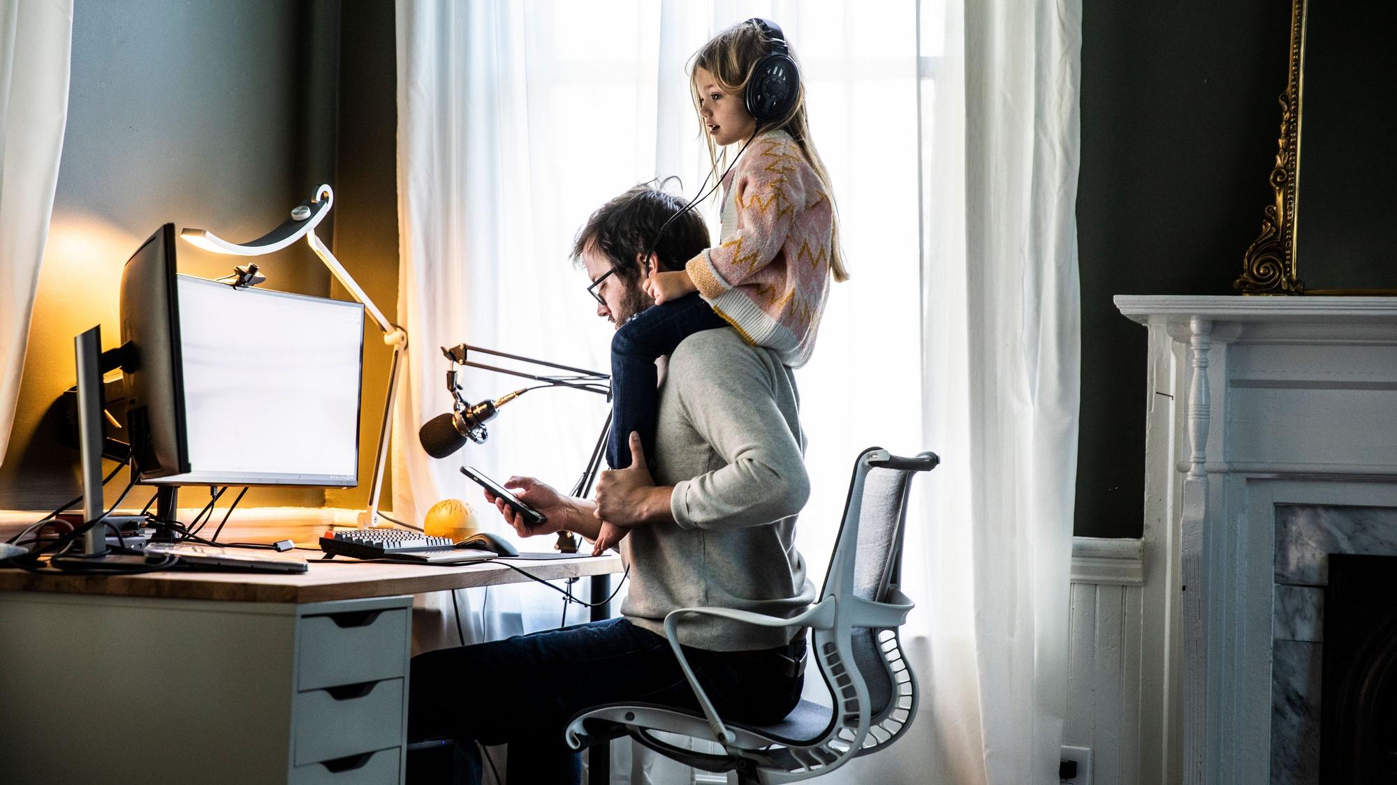 Vater im Büro mit Tochter auf den Schultern.