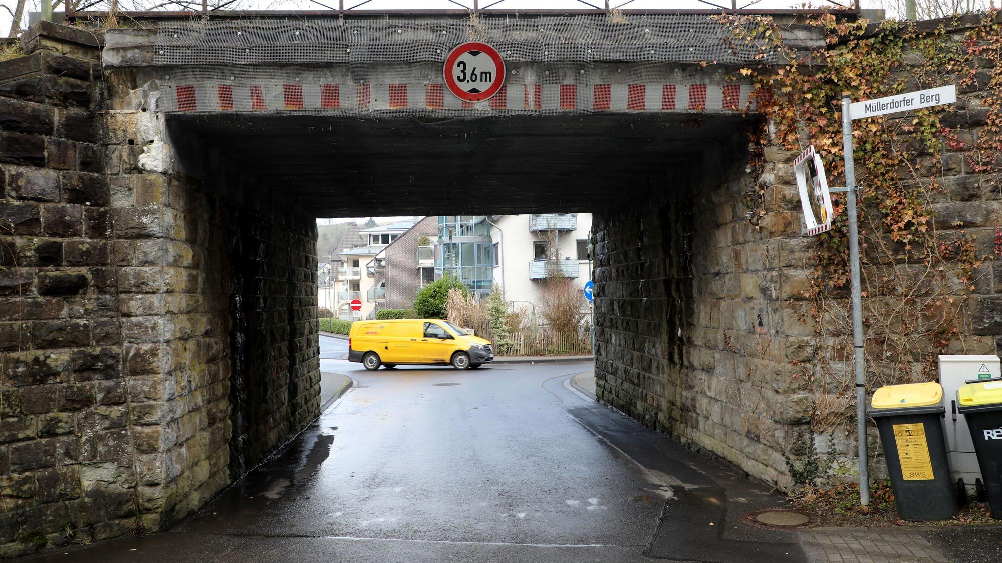 Eine enge Durchfahrt mit nasser Straße, am Ende der Durchfahrt ein Postauto