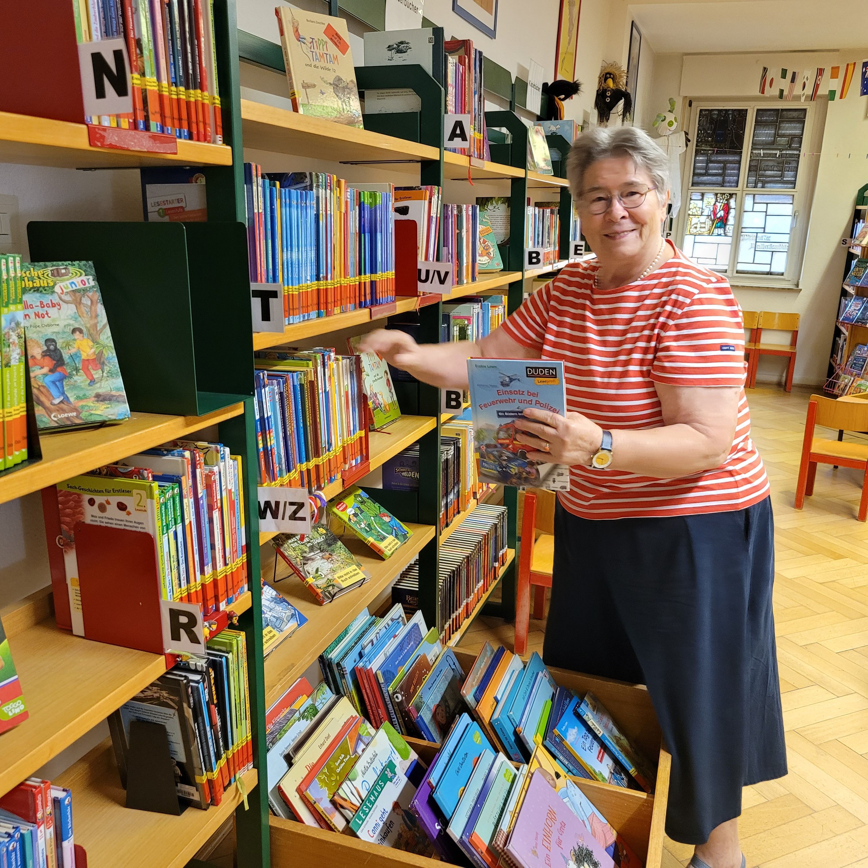 Auf dem Bild ist eine Frau zu sehen, die ein Buch aus einem Regal nimmt.