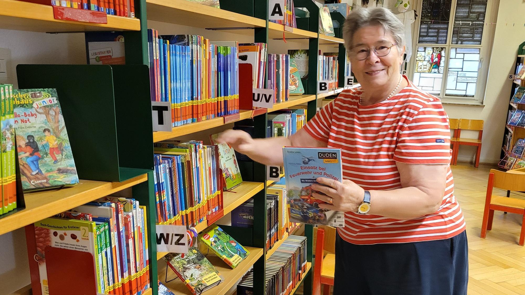 Auf dem Bild ist eine Frau zu sehen, die ein Buch aus einem Regal nimmt.