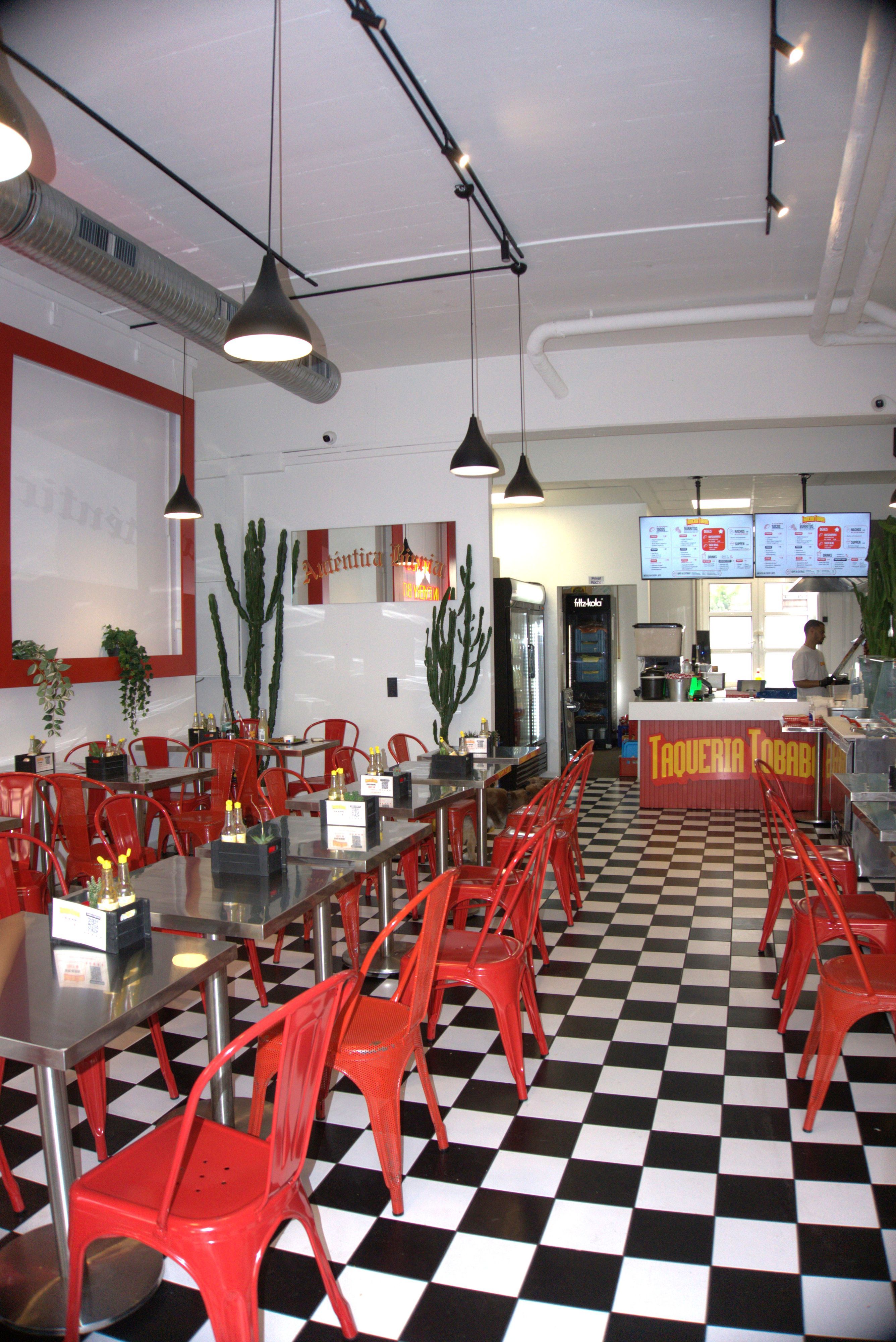 Die Taqueria Tobabo von innen mit roten Stühlen und silbernen Tischen.