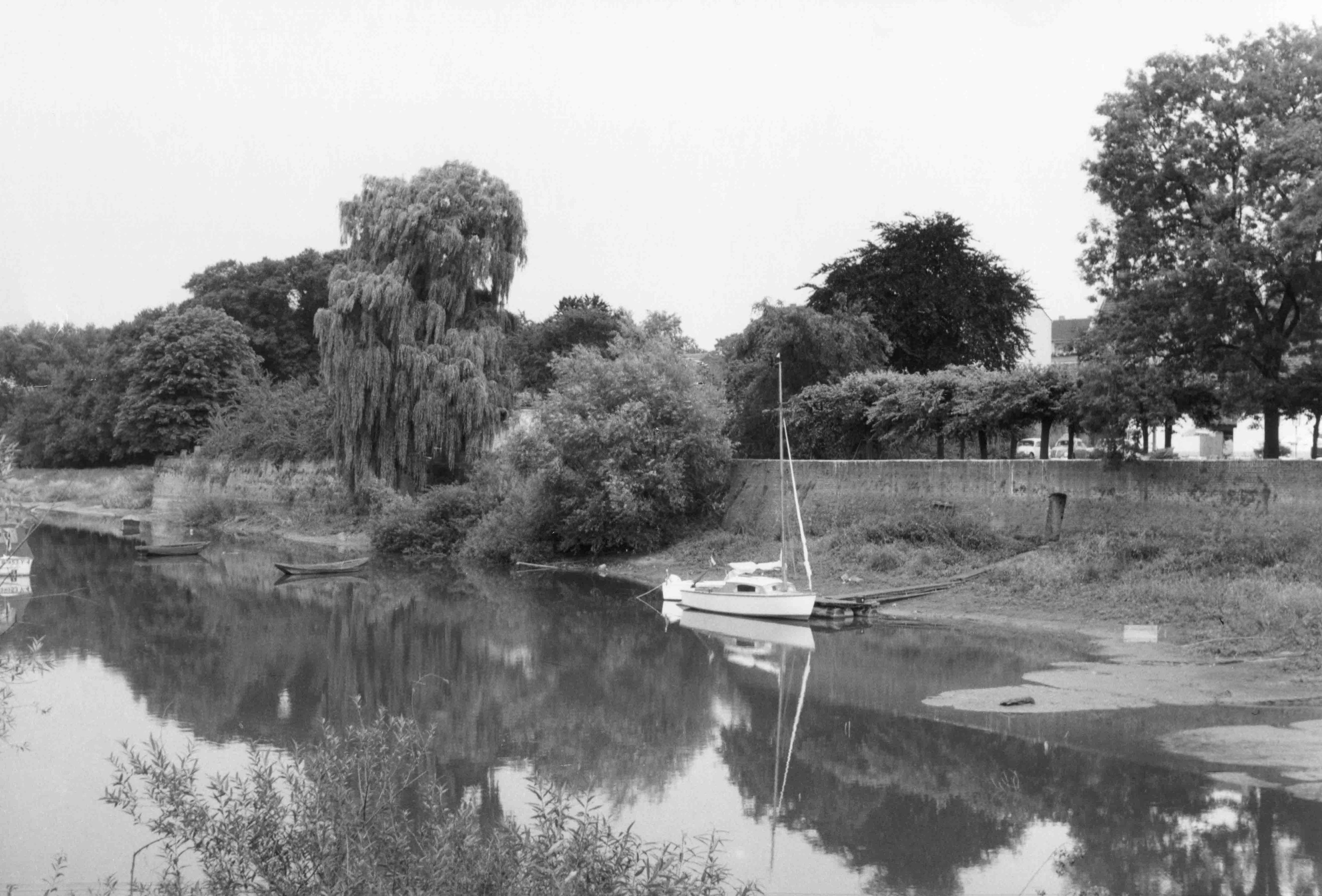 Historisches Schwarz-Weiß-Bild: Am toten Rheinarm gab es keine Anlegestelle, Boote mussten über eine Kuhweide bis zu einer schmalen Wasserverbindung zum Rhein getragen werden. Später entstand hier der Hafen.
