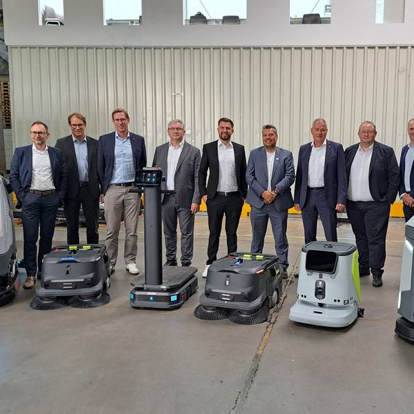 Das Foto zeigt eine Gruppe von Männern und davor einige Roboter.