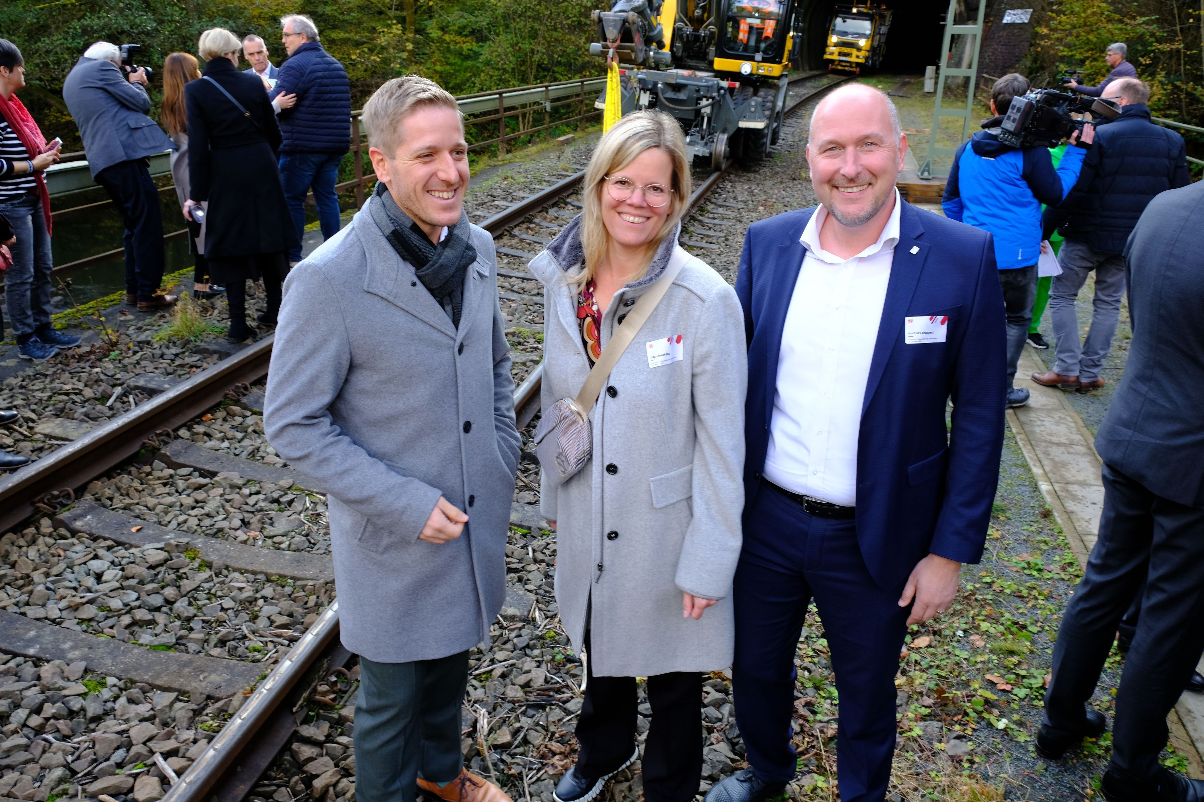 Die Landräte und der heutige ADD-Chef stehen neben einer Eisenbahntrasse.