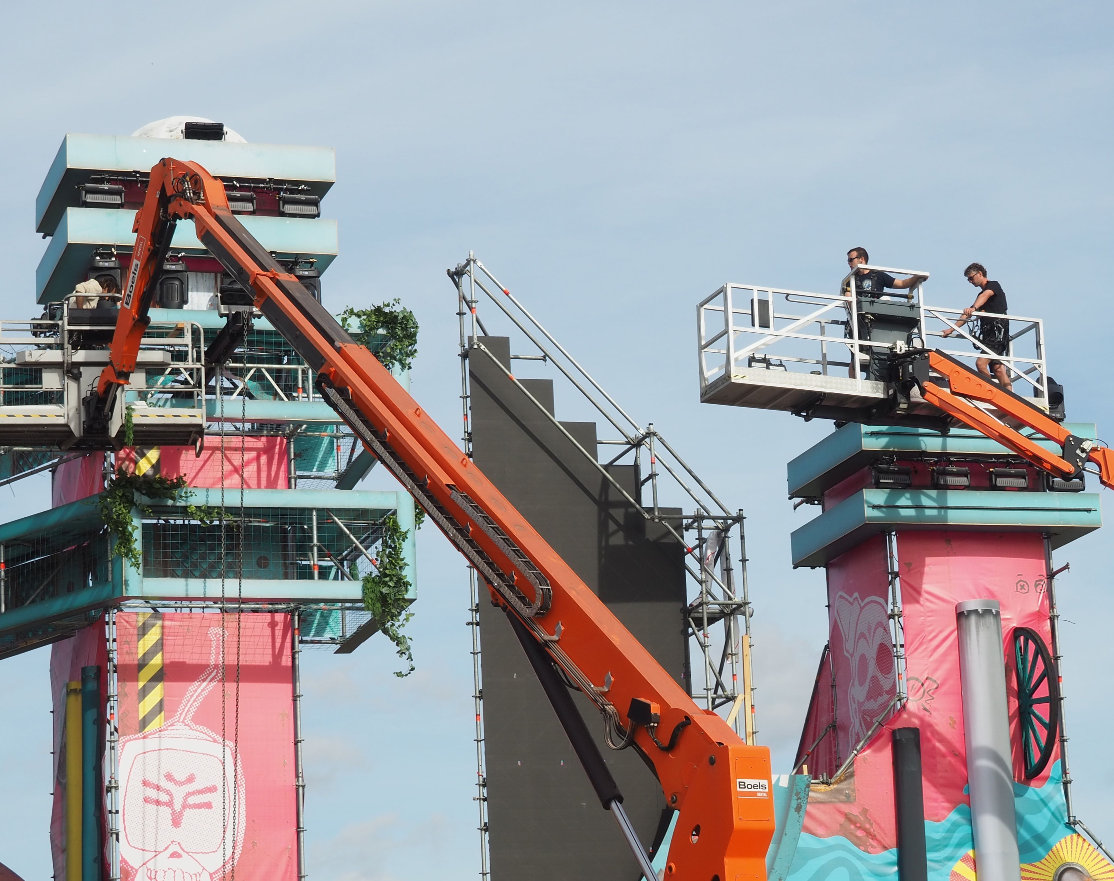 Zwei Männer arbeiten im Korb eines Hubsteigers und bauen die Bühne für das Madness-Festival in Zülpich auf.