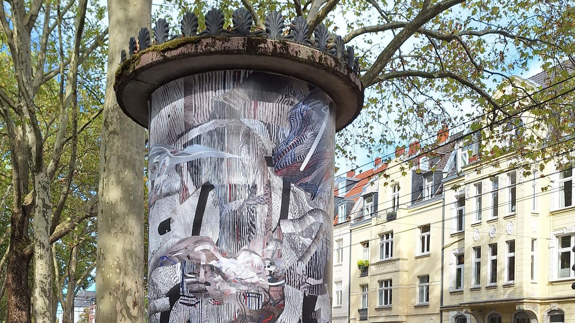 Eine Litfaßsäule der Aktion „Kunst an Kölner Litfaßsäulen“ zeigt die Arbeit „Palimpsest“ der Künstlerin Karin Hochstatter.
