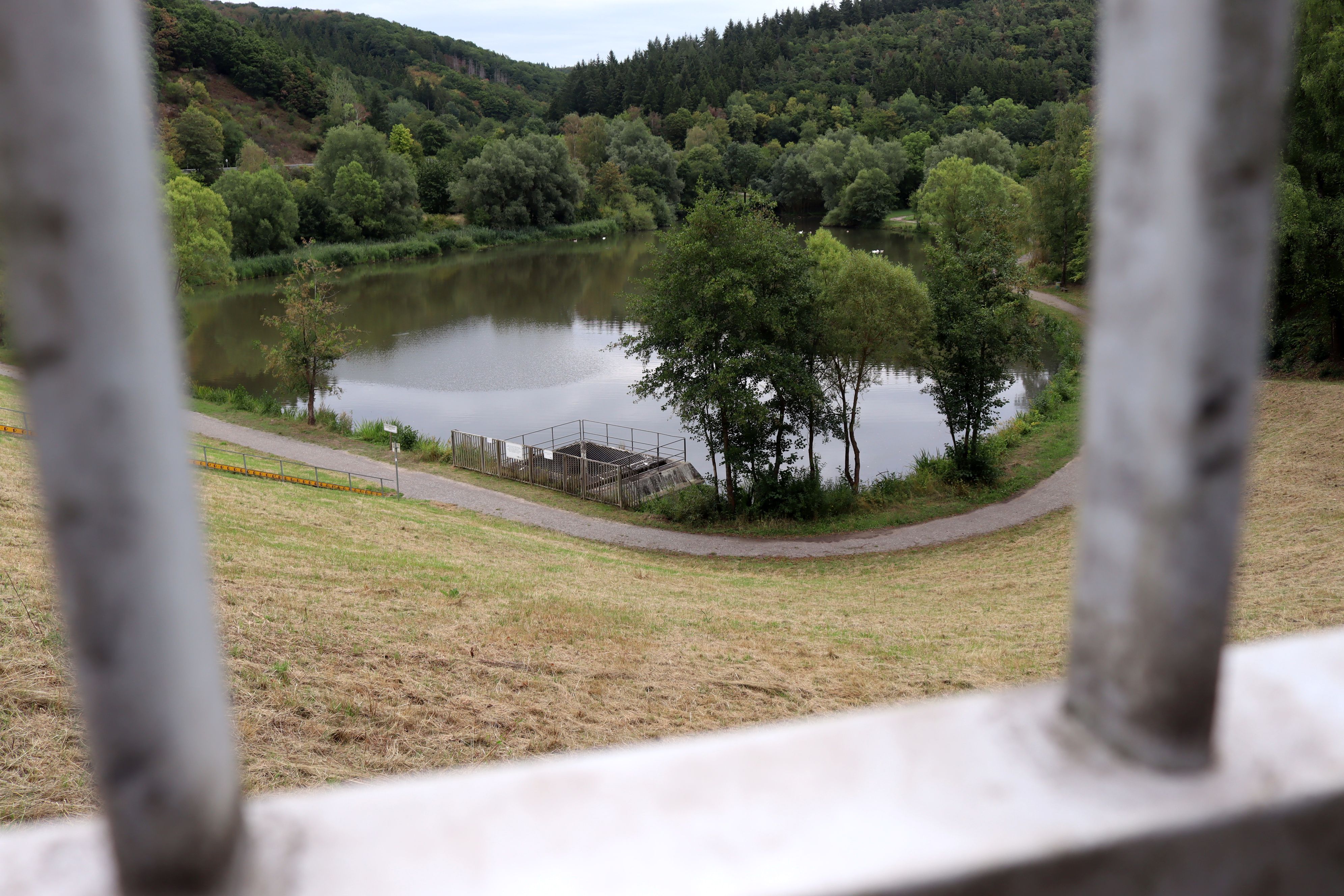 Hinter Gitterstäben ist das Hochwasserrückhaltebecken in Eicherscheid zu sehen.
