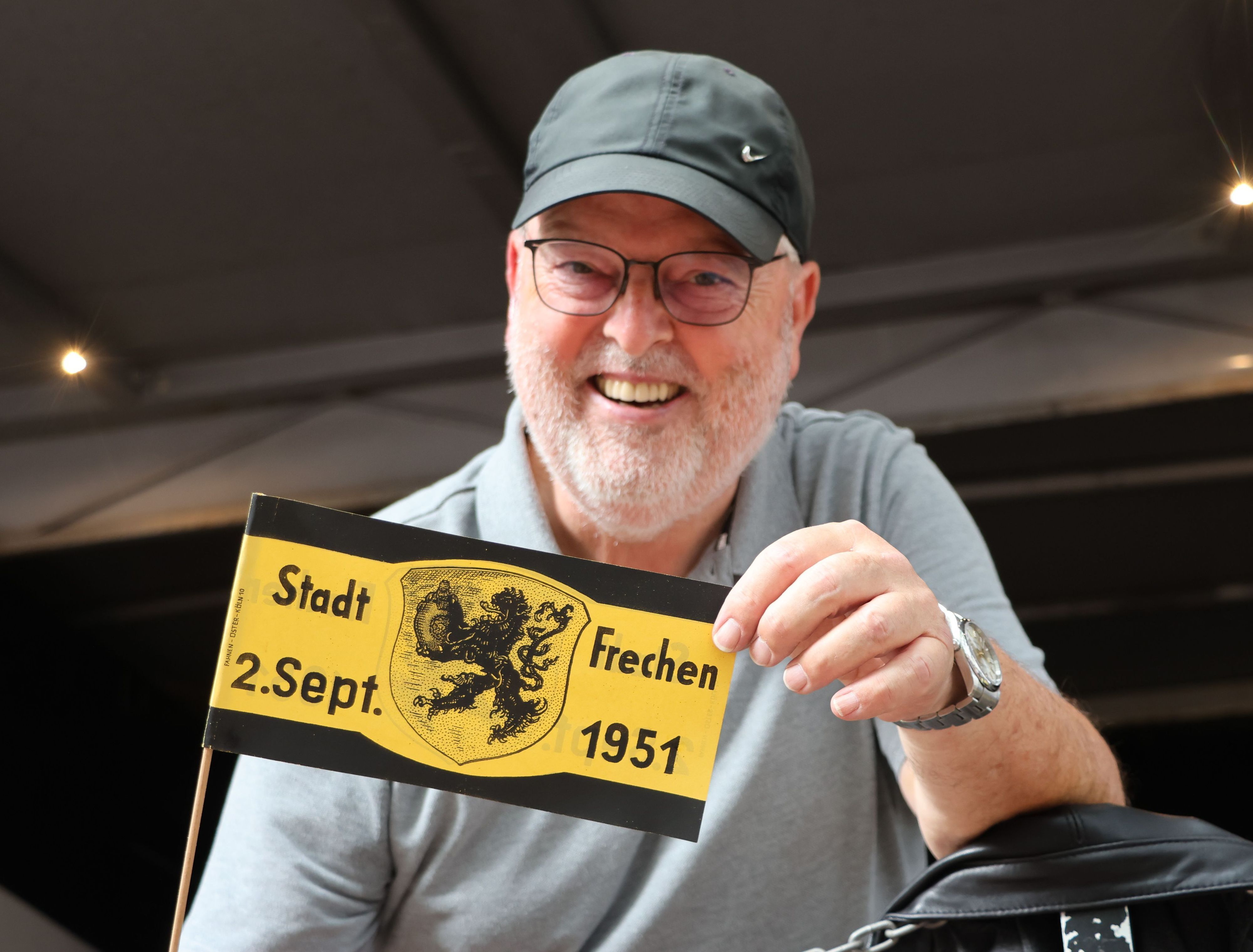 Auf dem Bild ist ein Mann zu sehen, der eine Orginalfahne aus dem Jahr 1951 in die Kamera hält.