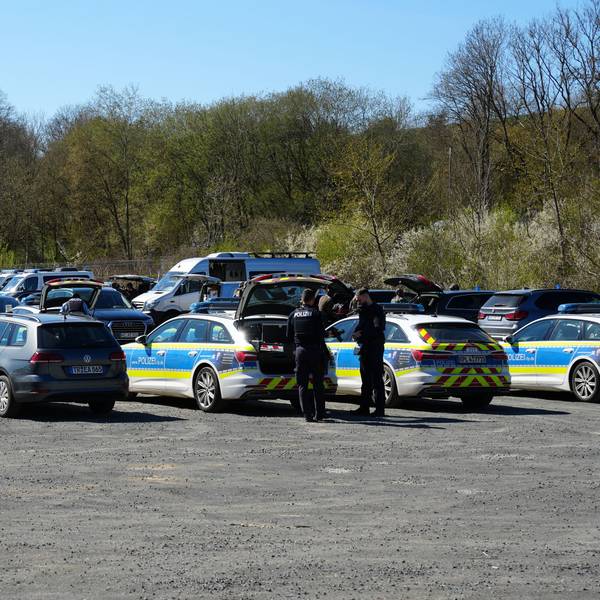 Polizisten stehen an ihren Fahrzeugen und bereiten sich in Prüm auf ihren Einsatz vor.