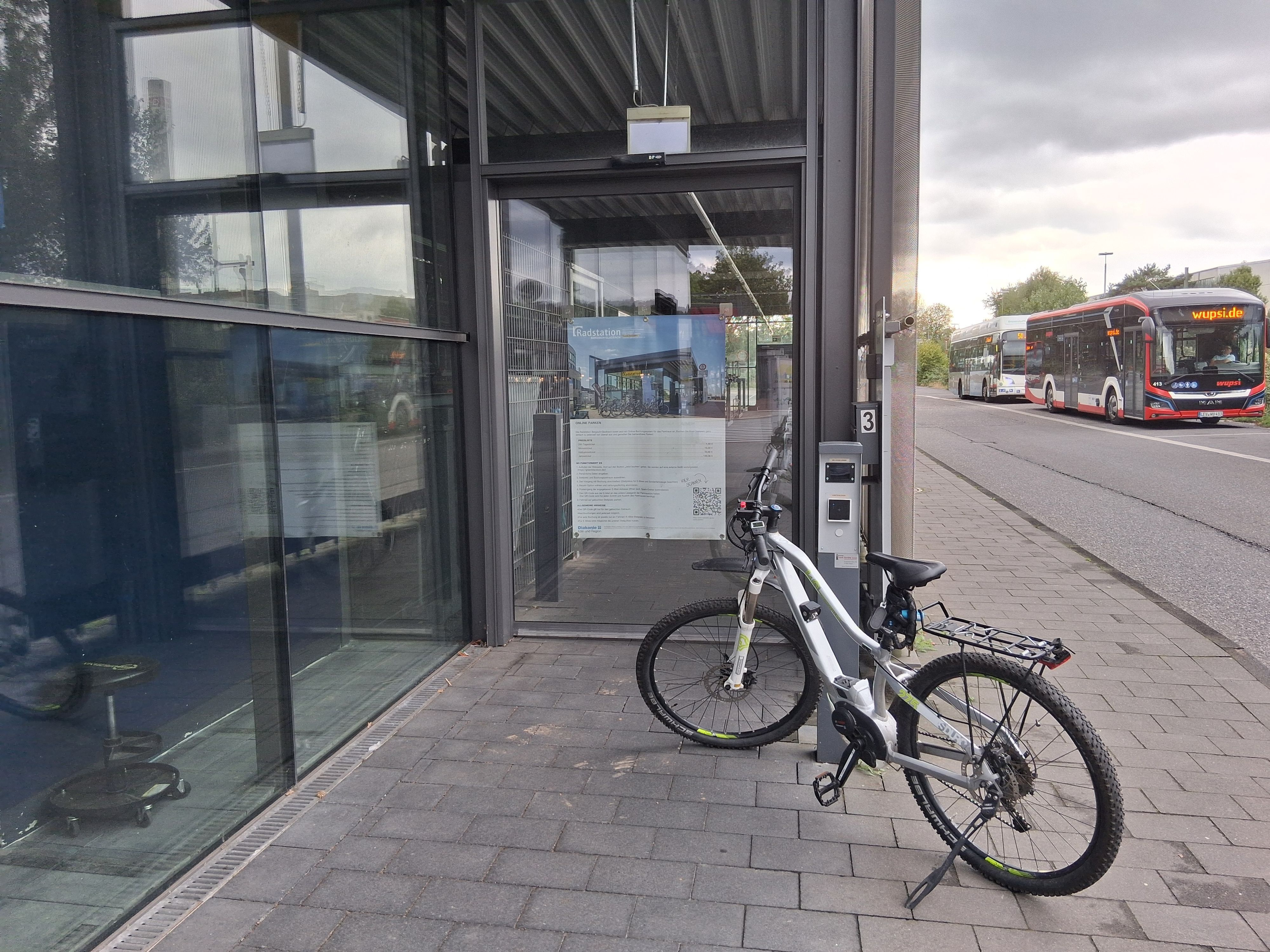 ein Fahrrad steht vor einer verschlossenen Glastür, an der ein Chiplesegerät angebracht ist