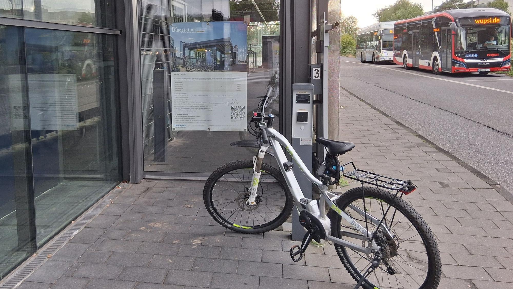 ein Fahrrad steht vor einer verschlossenen Glastür, an der ein Chiplesegerät angebracht ist