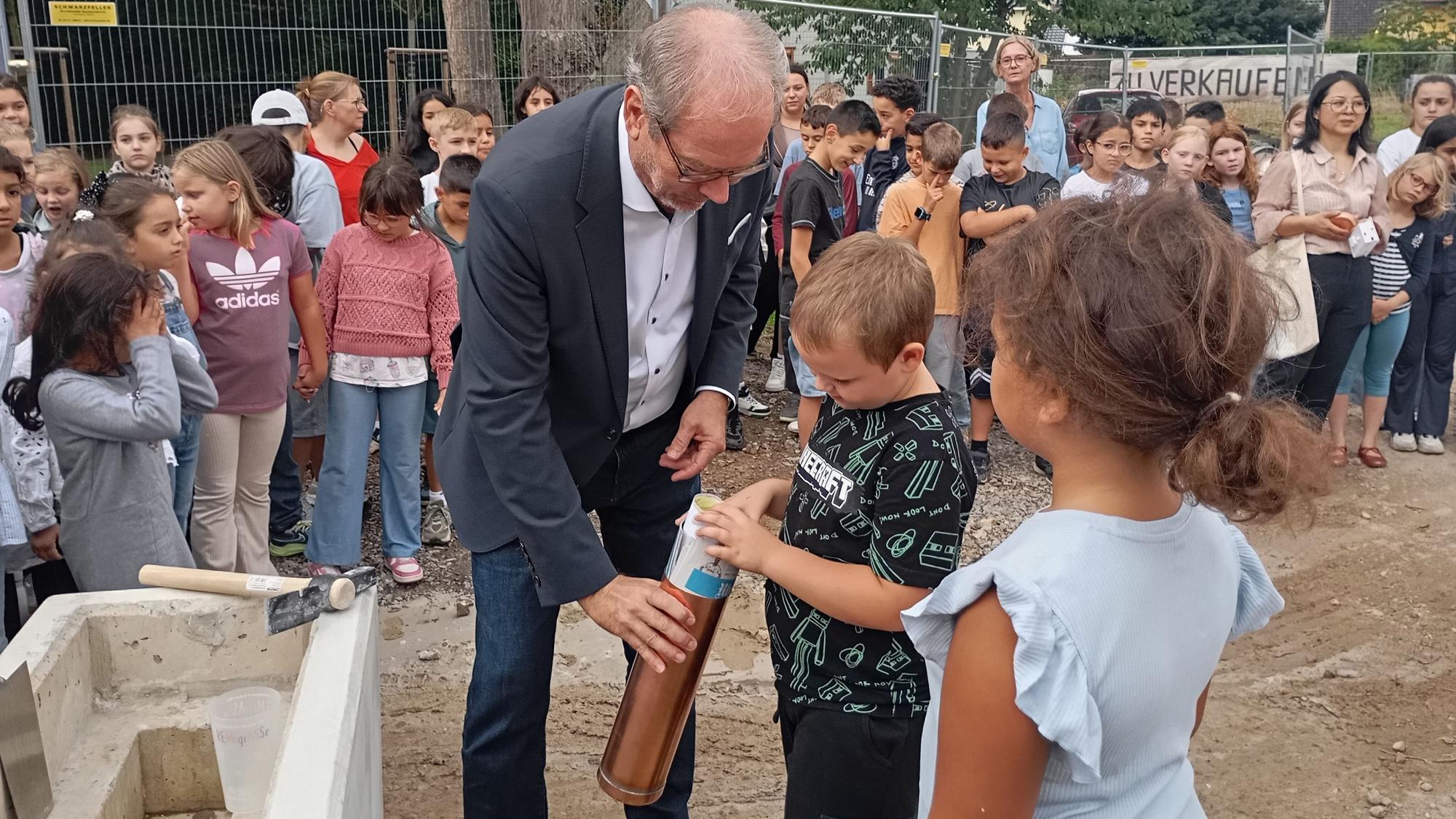 Zu sehen sind Bergheims Bürgermeister Volker Mießeler und zwei Kinder.